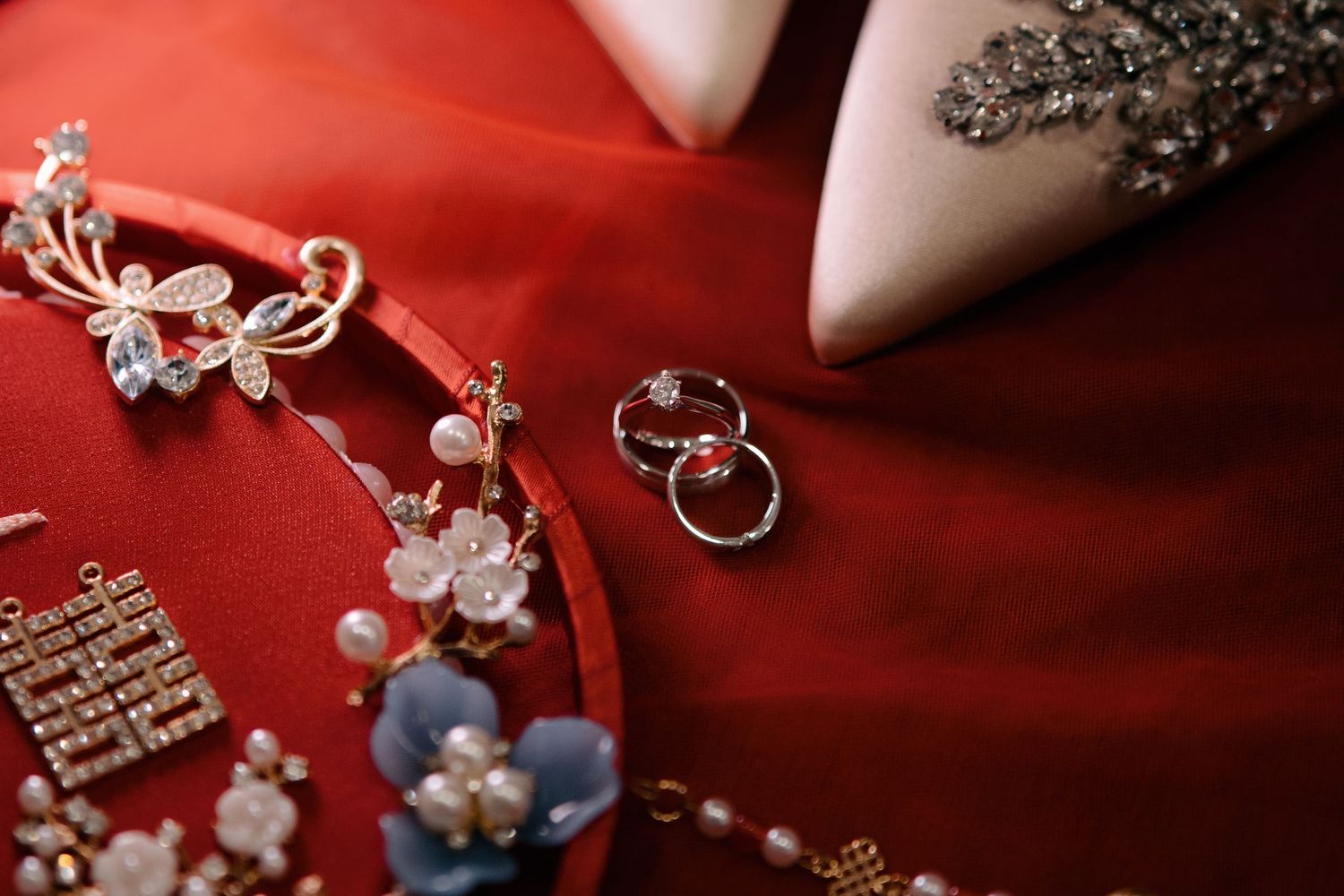 Close-up of silver wedding rings placed next to a jeweled floral hairpin and a 