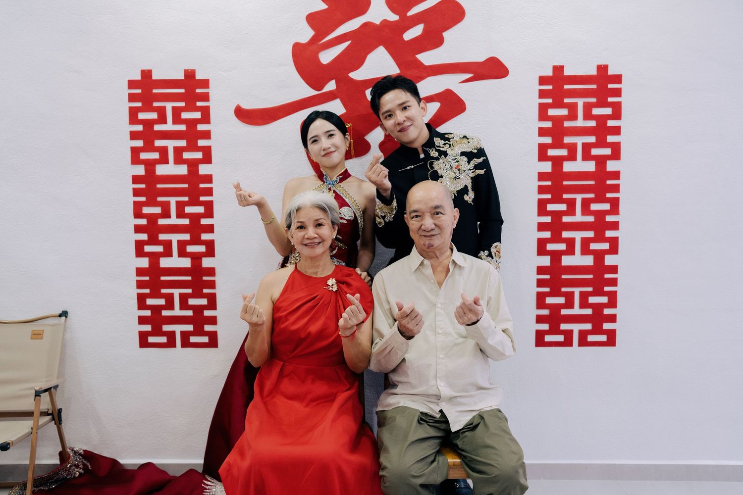 Couple and parents posing with finger hearts at a traditional Chinese wedding celebration