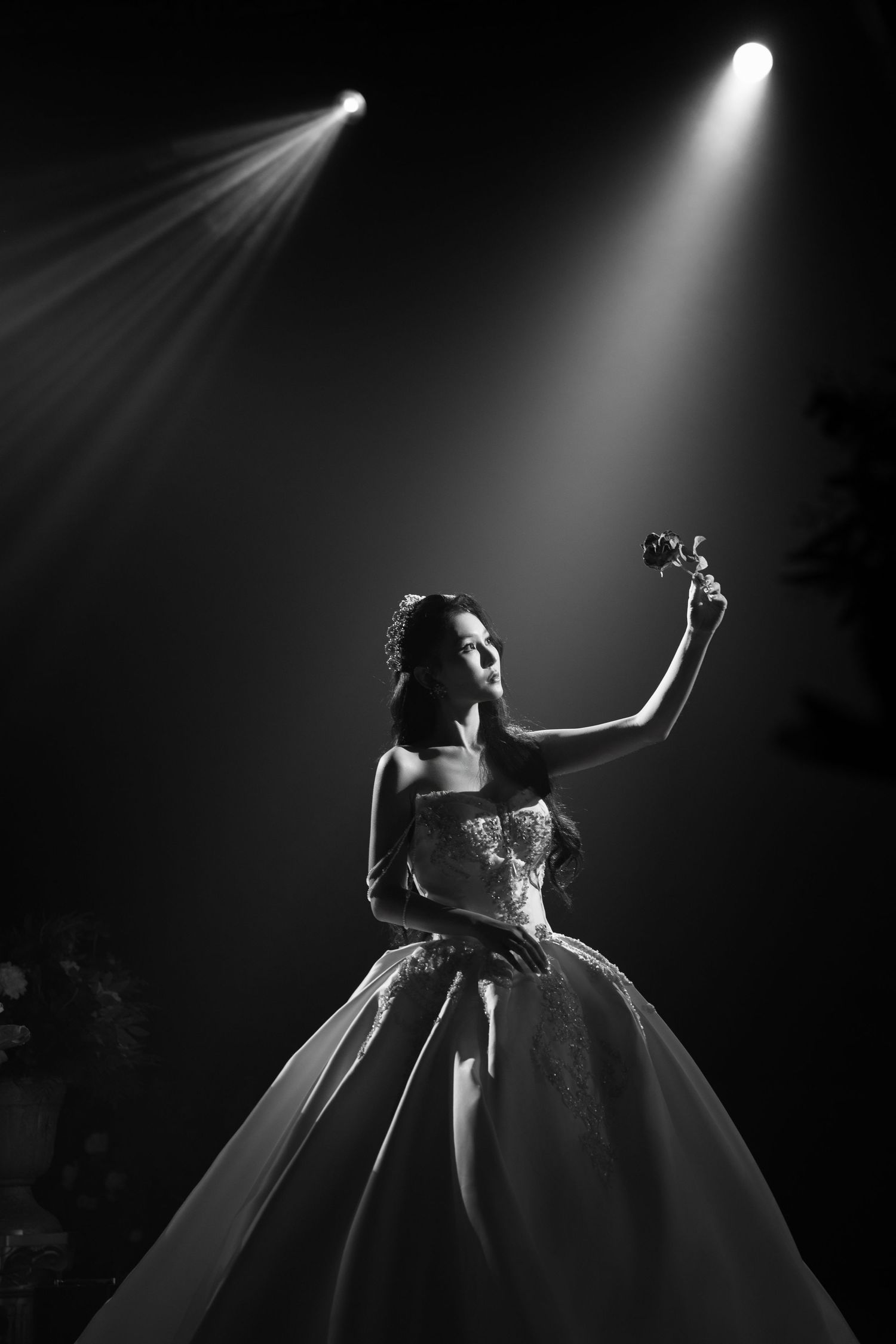 Bride holding a rose under a spotlight for a Beauty and the Beast inspired wedding theme