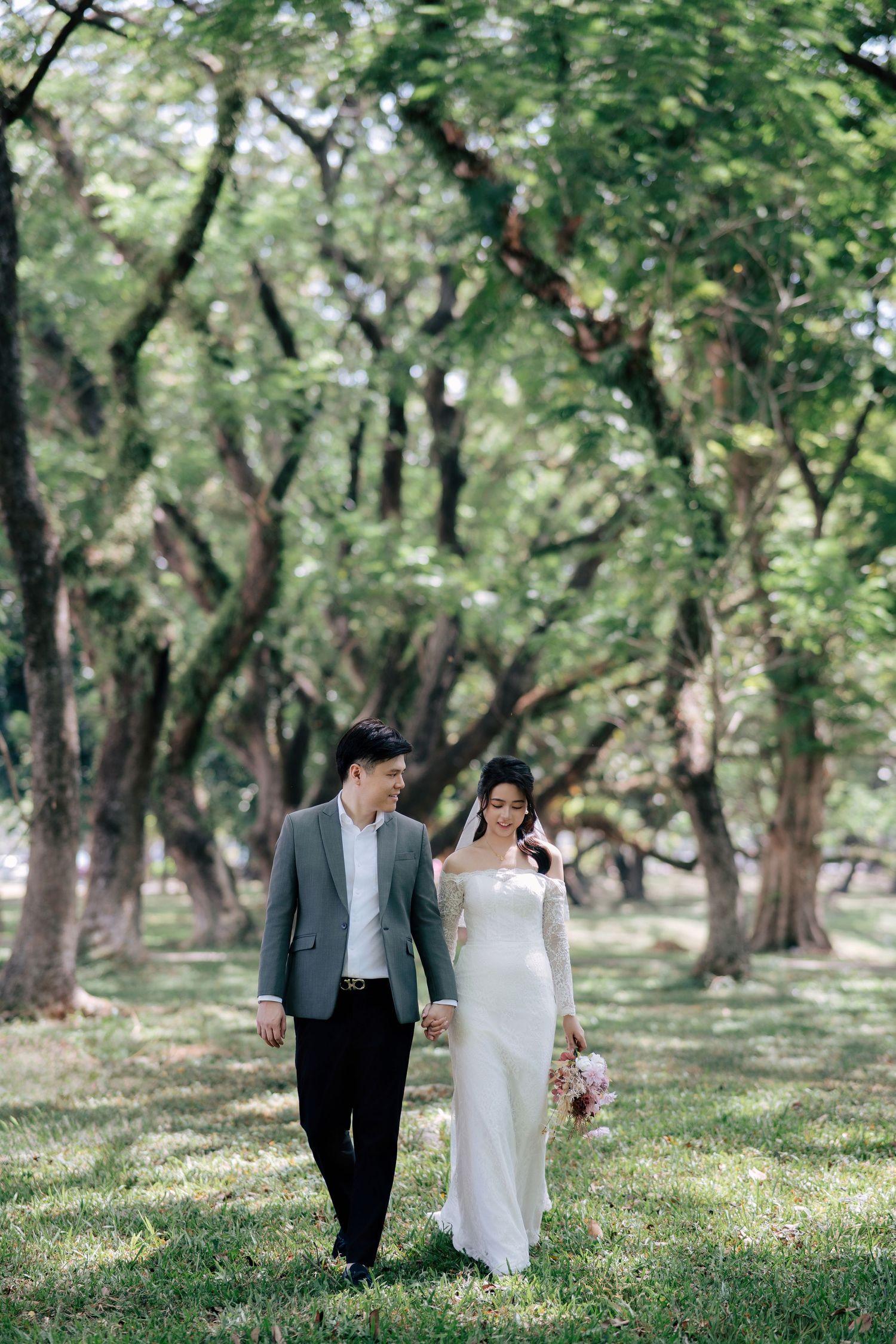 Newlyweds share intimate moments while walking through a sunlit park.