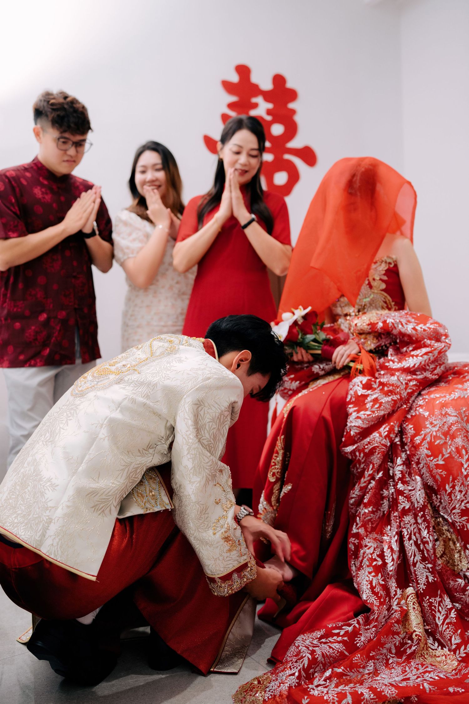 Wedding party members in white and red attire participate in traditional ceremonies.