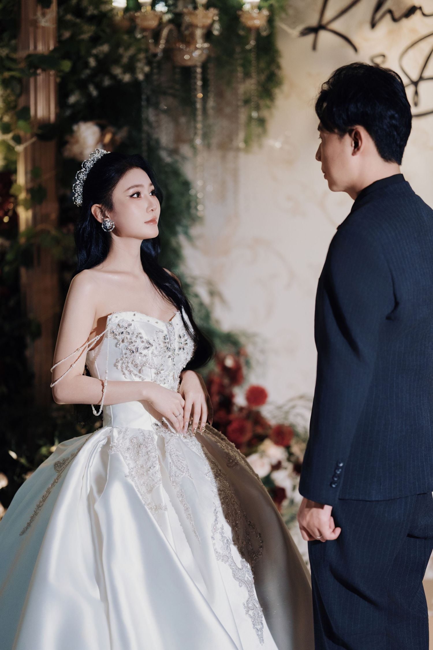 Romantic couple portrait at a luxury wedding reception featuring a forest-themed floral backdrop