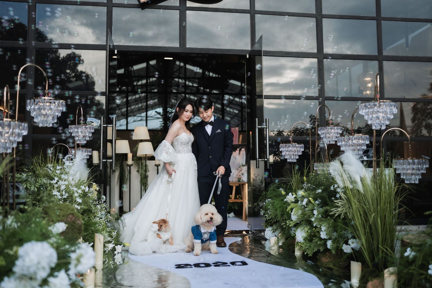 Bride and groom posing with their dogs at a pet-friendly wedding ceremony with elegant floral decor and bubbles