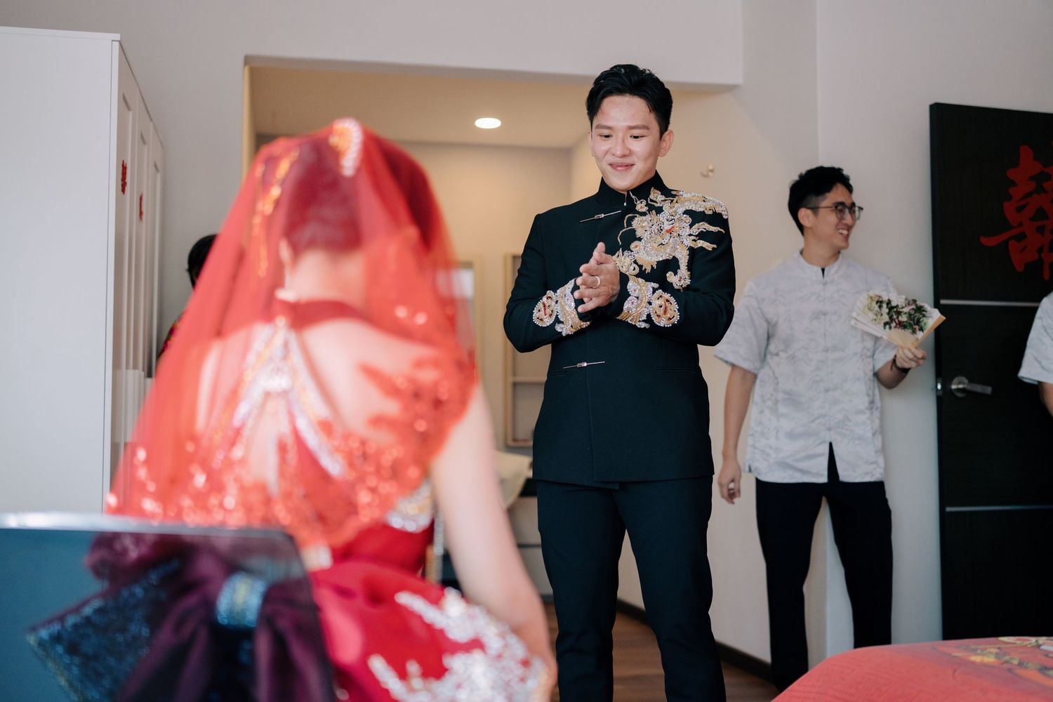 Groom performs a traditional greeting before his bride in a red Kua during a Chinese wedding