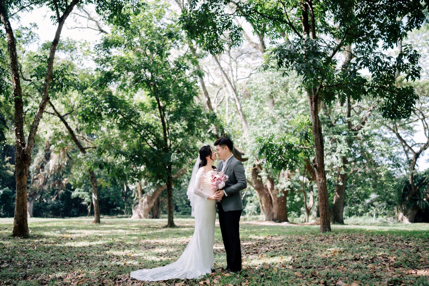 Wedding couple walking through a serene tree-lined park on their special day.