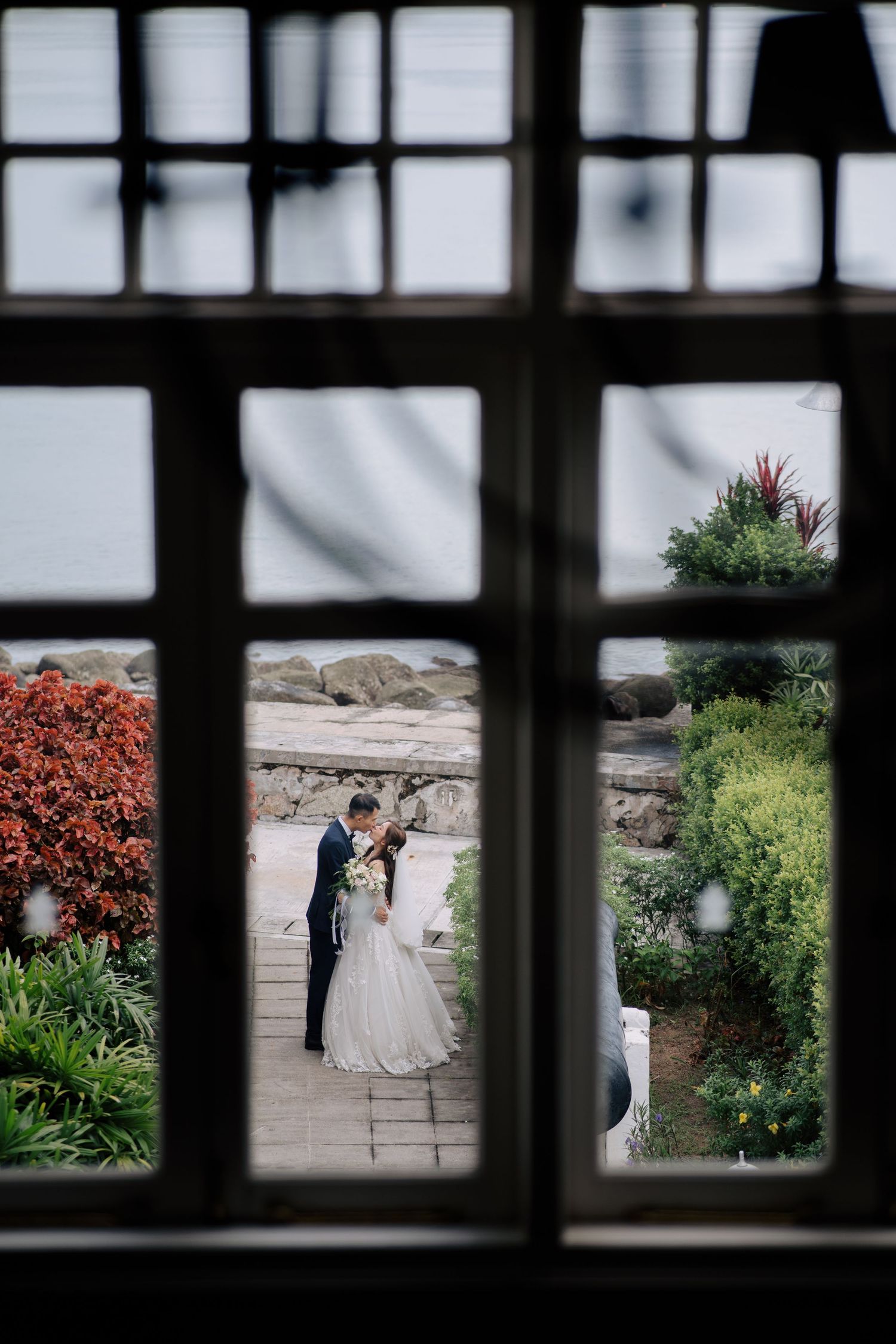Wedding scene viewed through window panes in an architectural setting.