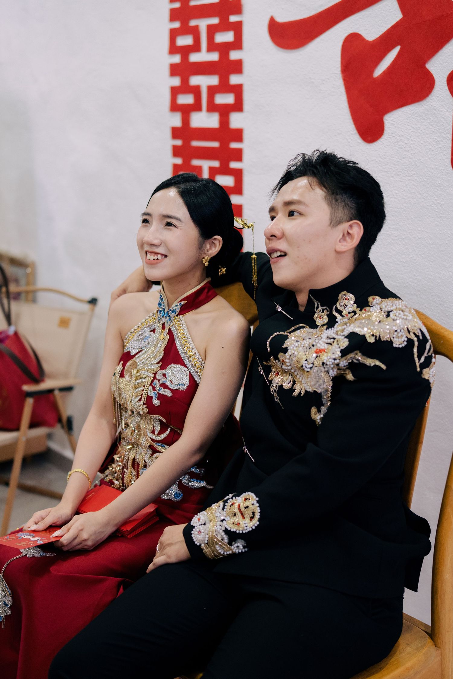 Happy couple in traditional Chinese wedding attire sitting together during their tea ceremony