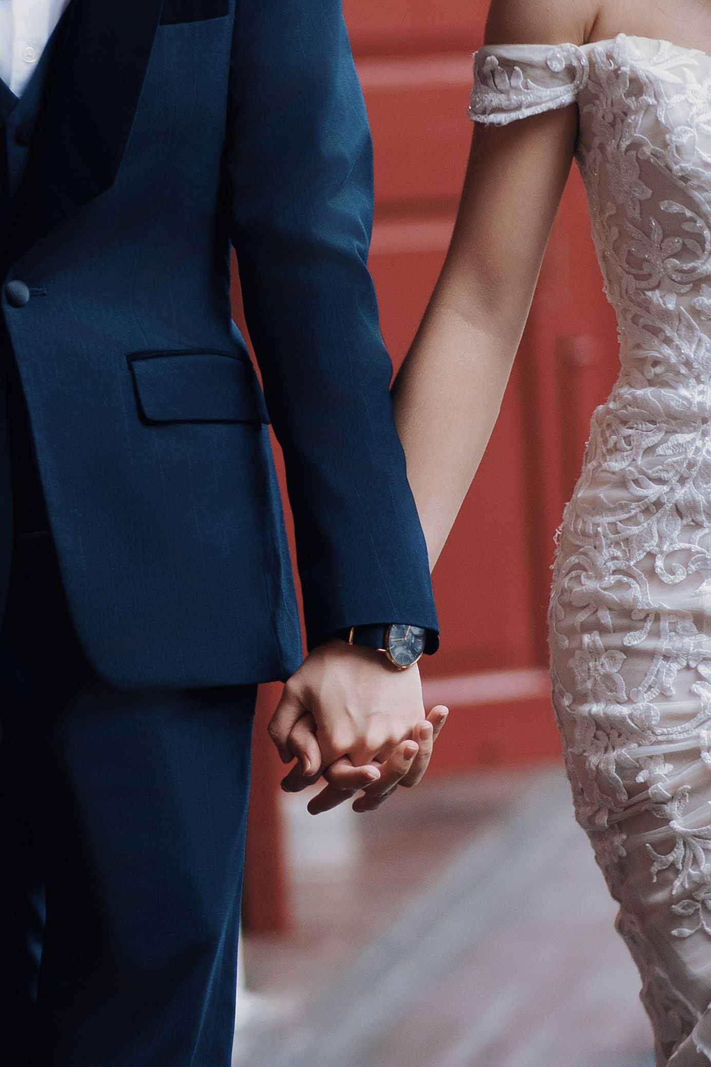 Close-up of a bride and groom holding hands at a luxury destination wedding Penang, featuring lace and suit details