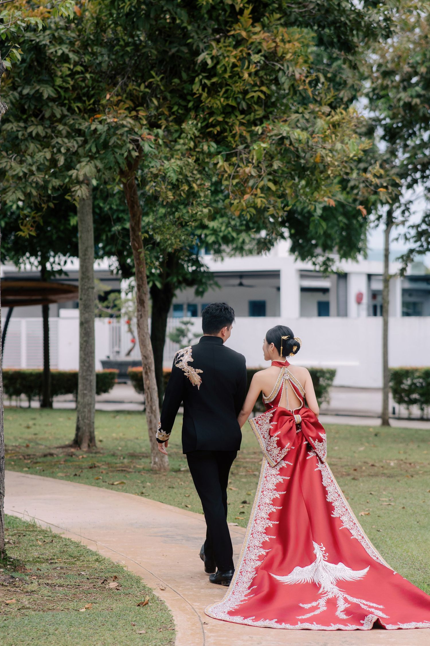Detailed back view of a modern red qipao with an ornate phoenix train at a traditional Chinese wedding celebration