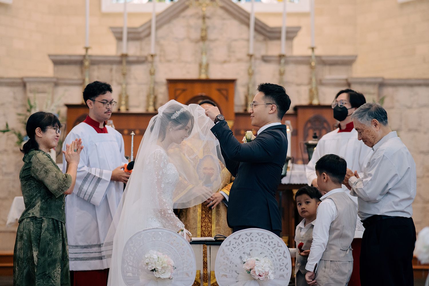 Groom lifting the bride's veil during a Catholic church wedding ceremony in Church of the Immaculate Conception Penang