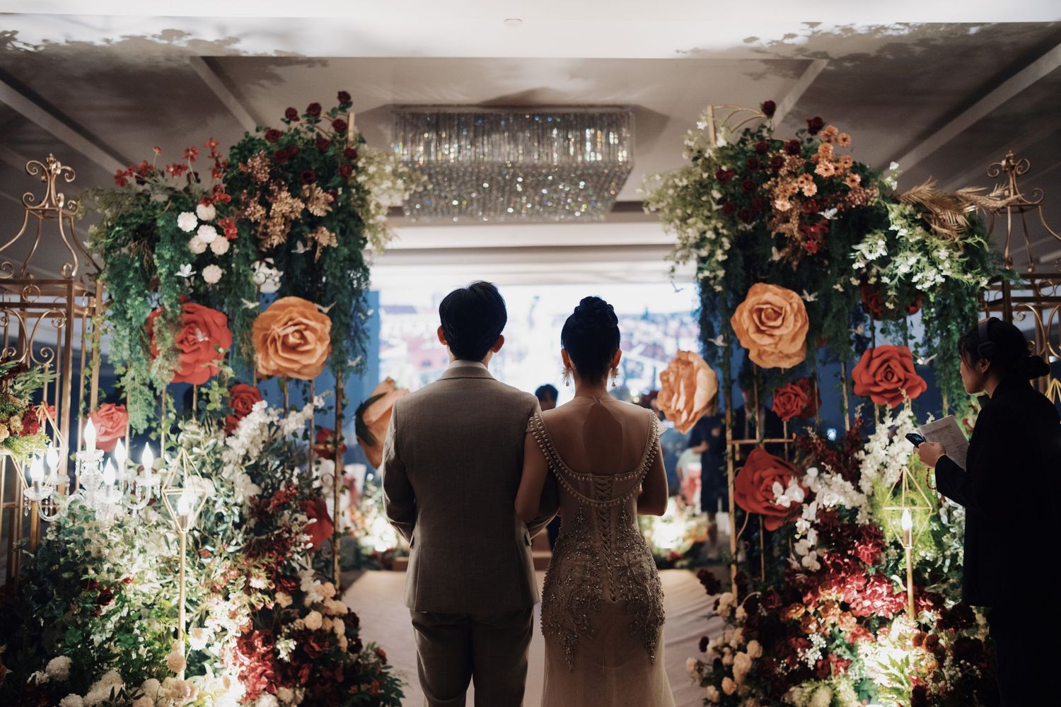 Couple’s perspective entering a grand wedding reception through massive rose floral displays