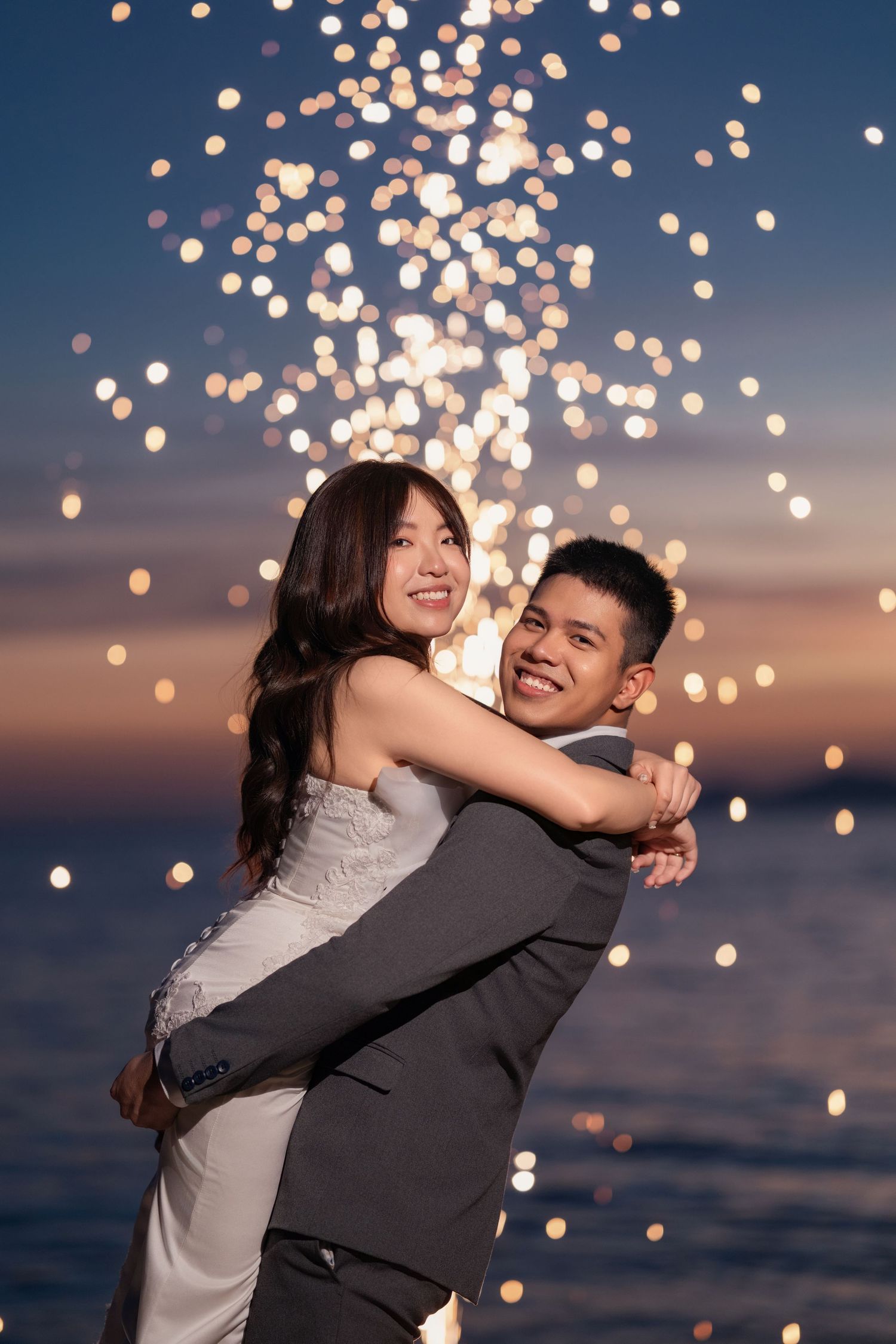 Joyful wedding celebration with floating bokeh lights creating a dreamy atmosphere by the ocean.