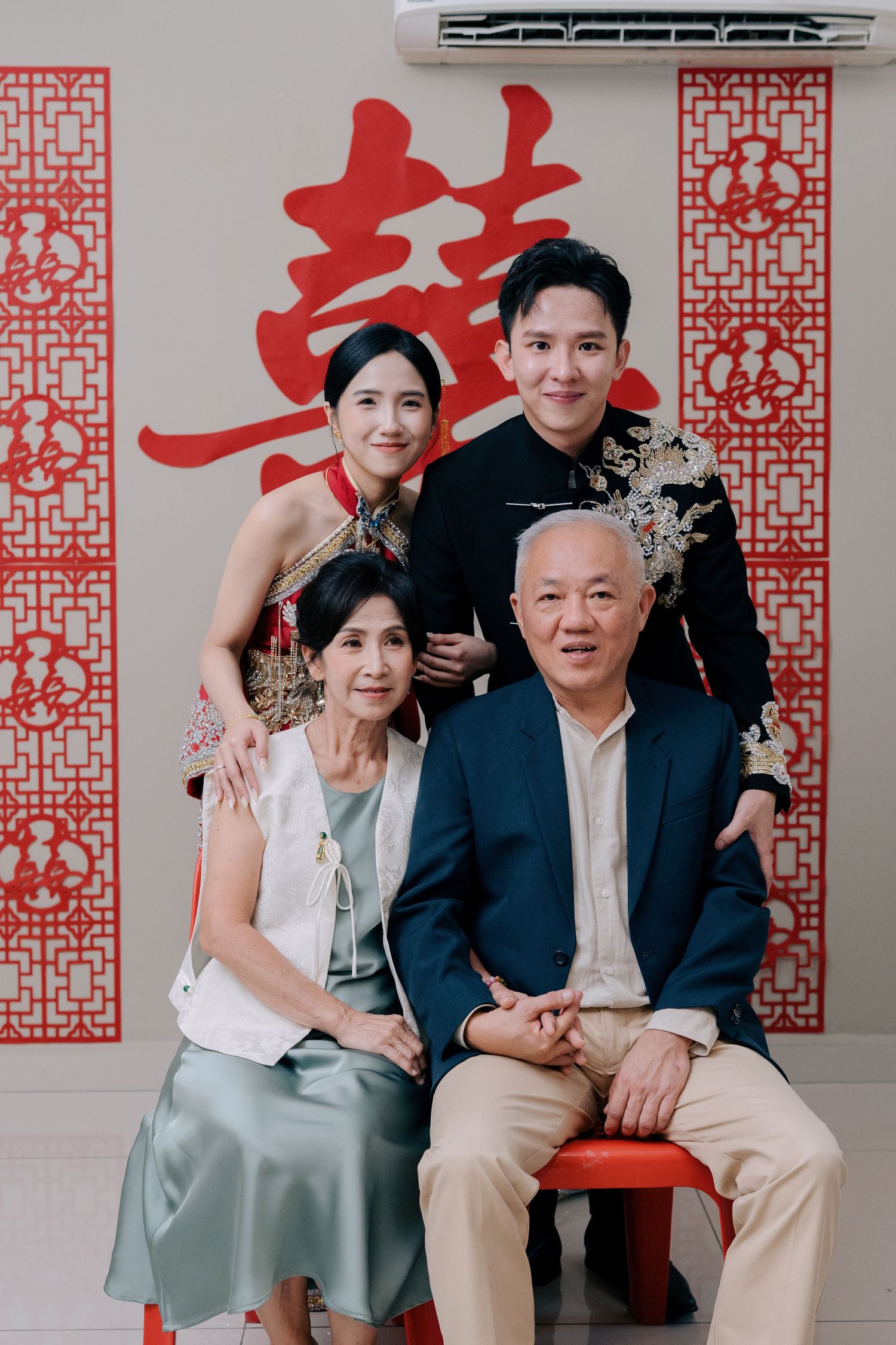 Bride and groom pose with parents under a red Xi symbol, capturing a key moment of a Traditional Chinese Wedding