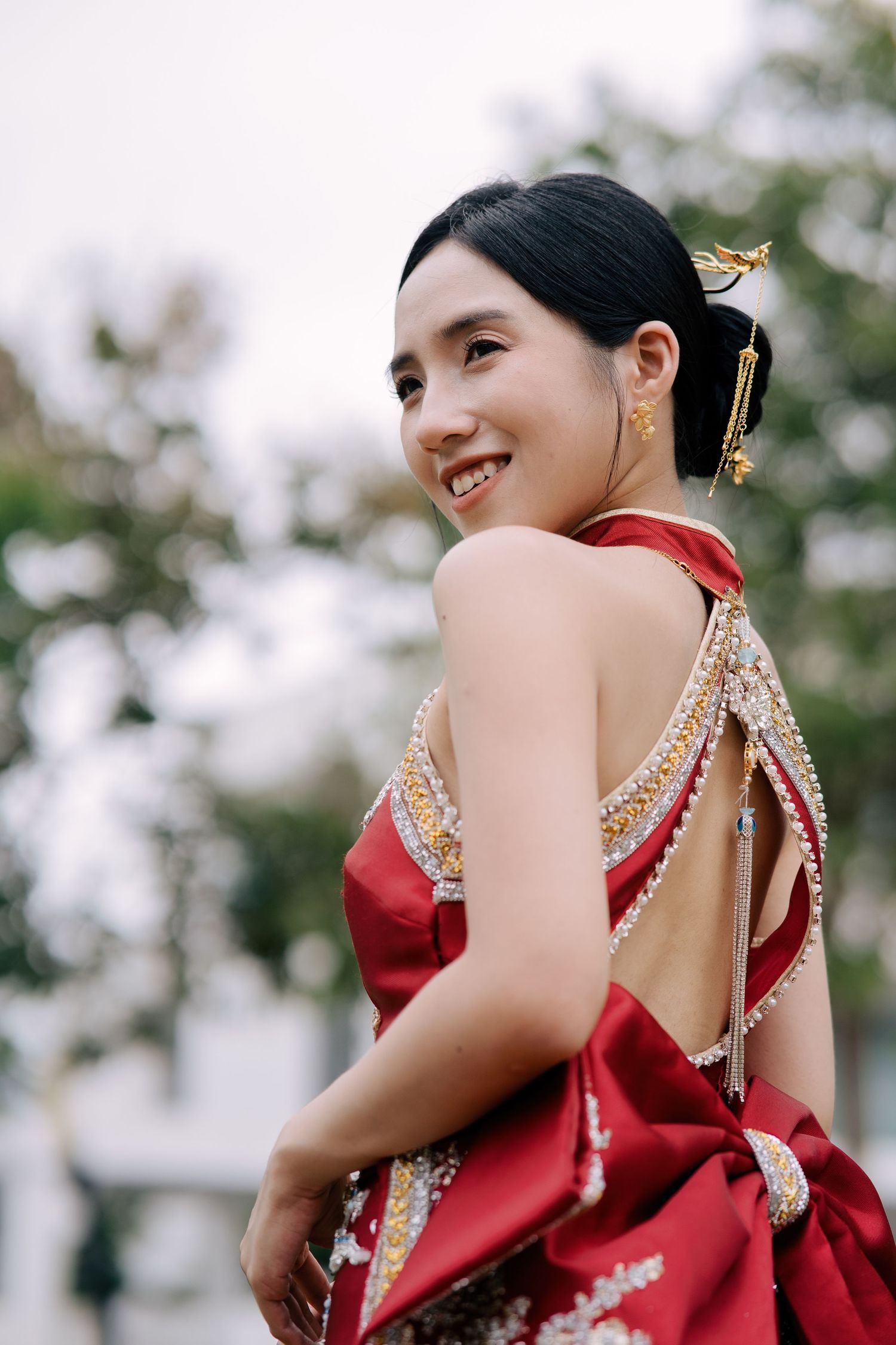 Bride showcases traditional gold hair ornaments and a beaded red oriental wedding gown