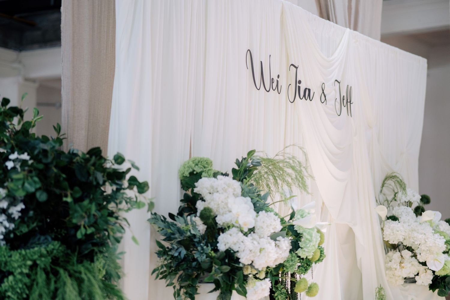 Peninsula House Penang wedding stage featuring minimal white drapes and lush green and white flowers