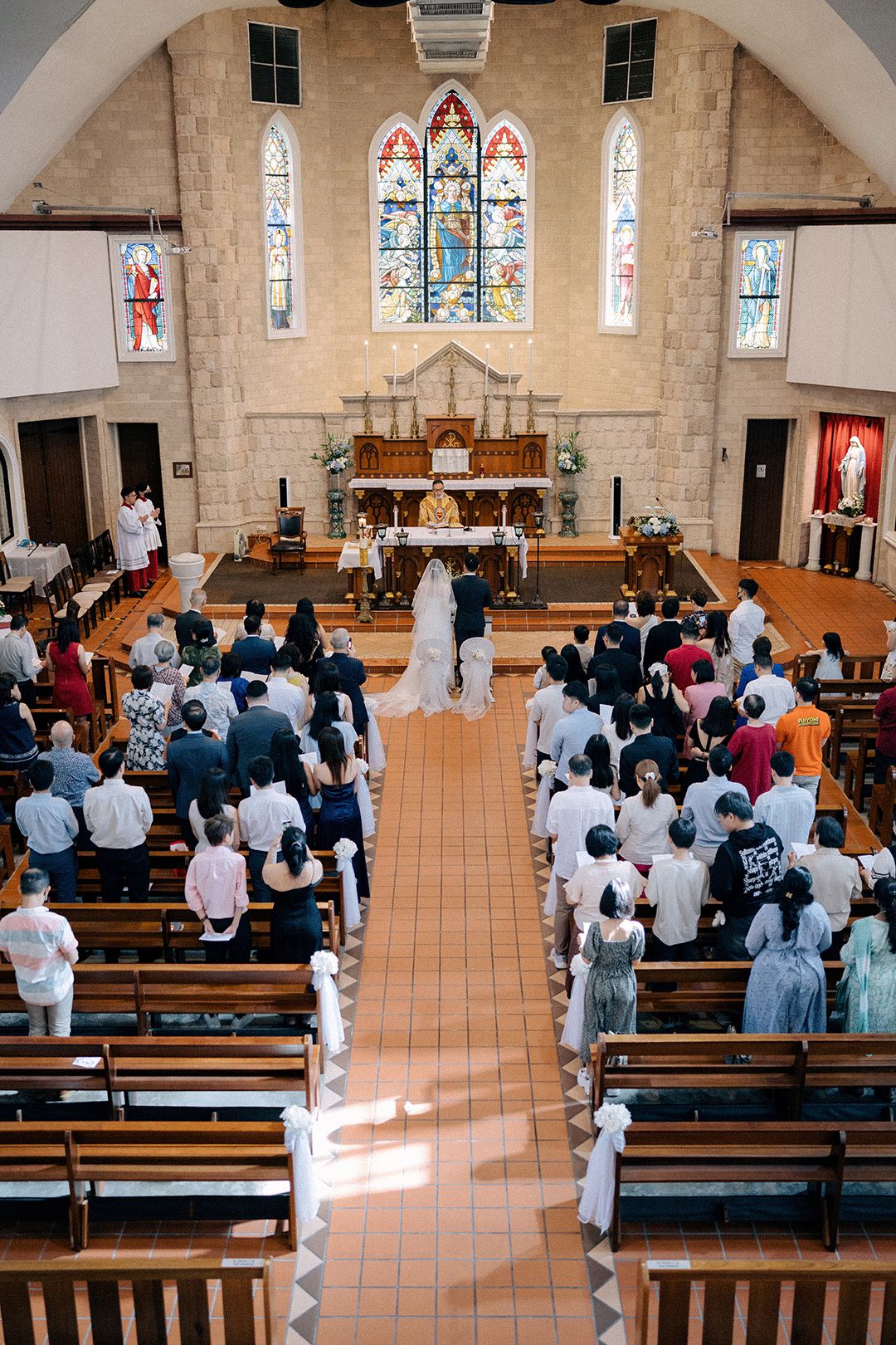 Interior view of a church wedding ceremony with guests seated in wooden pews.
