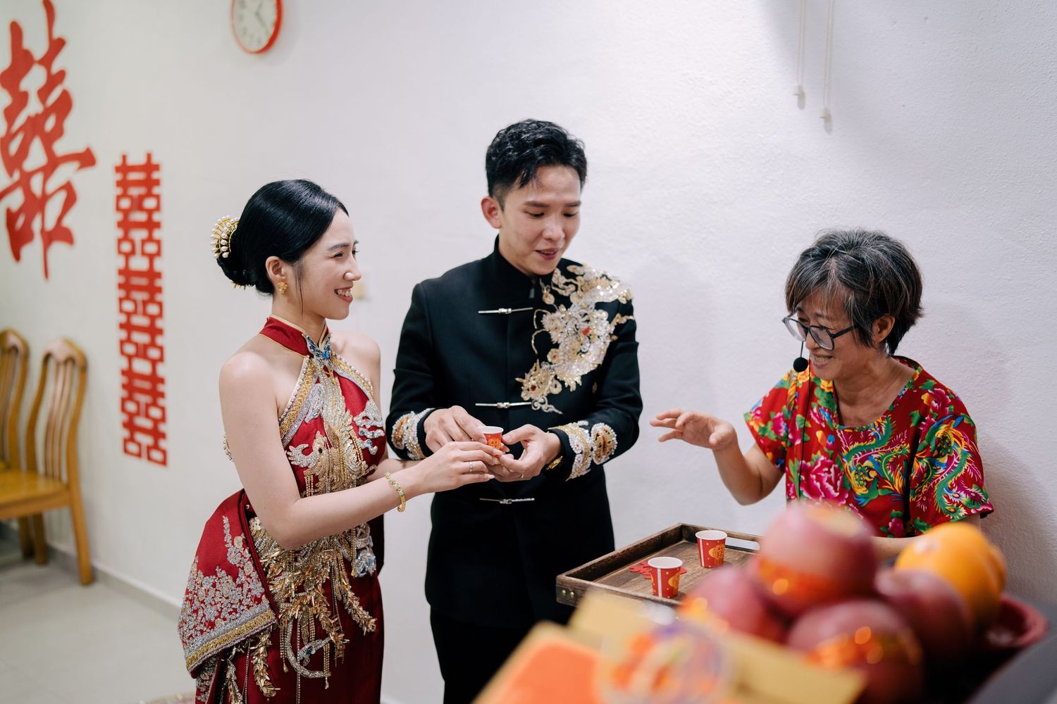Bride and groom holding a ceremonial tea cup during their traditional Chinese wedding celebration