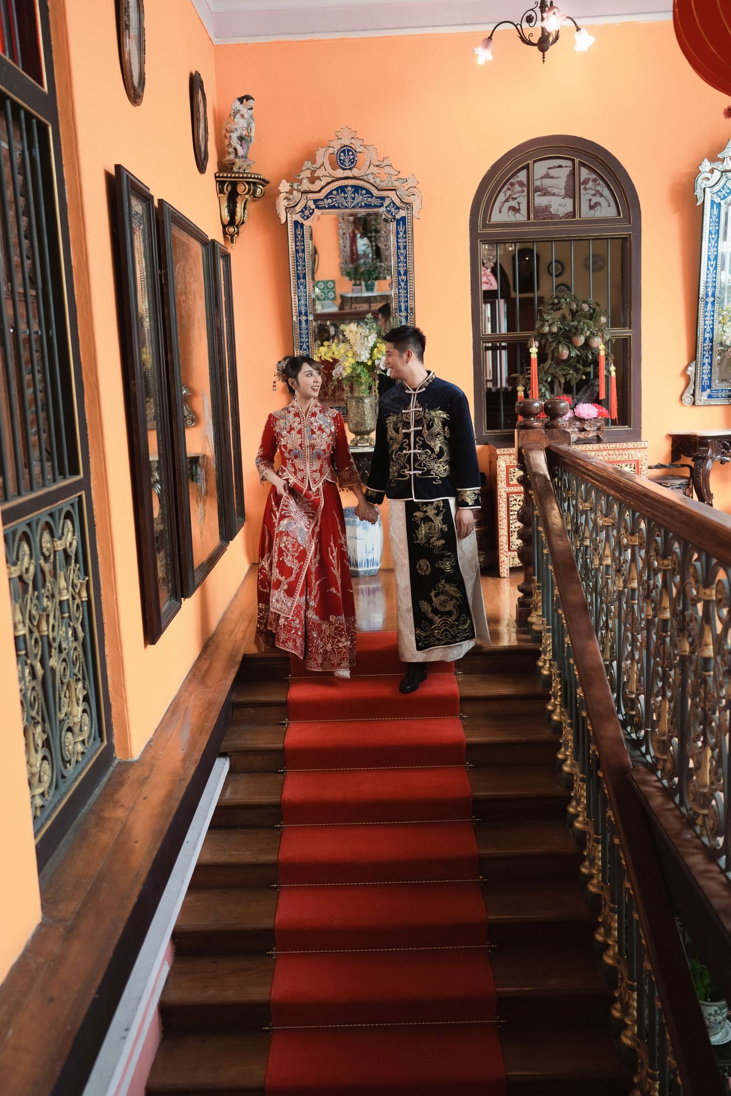 Romantic Peranakan wedding photography featuring a bride in a red Kua and groom in a dragon robe on a historic staircase