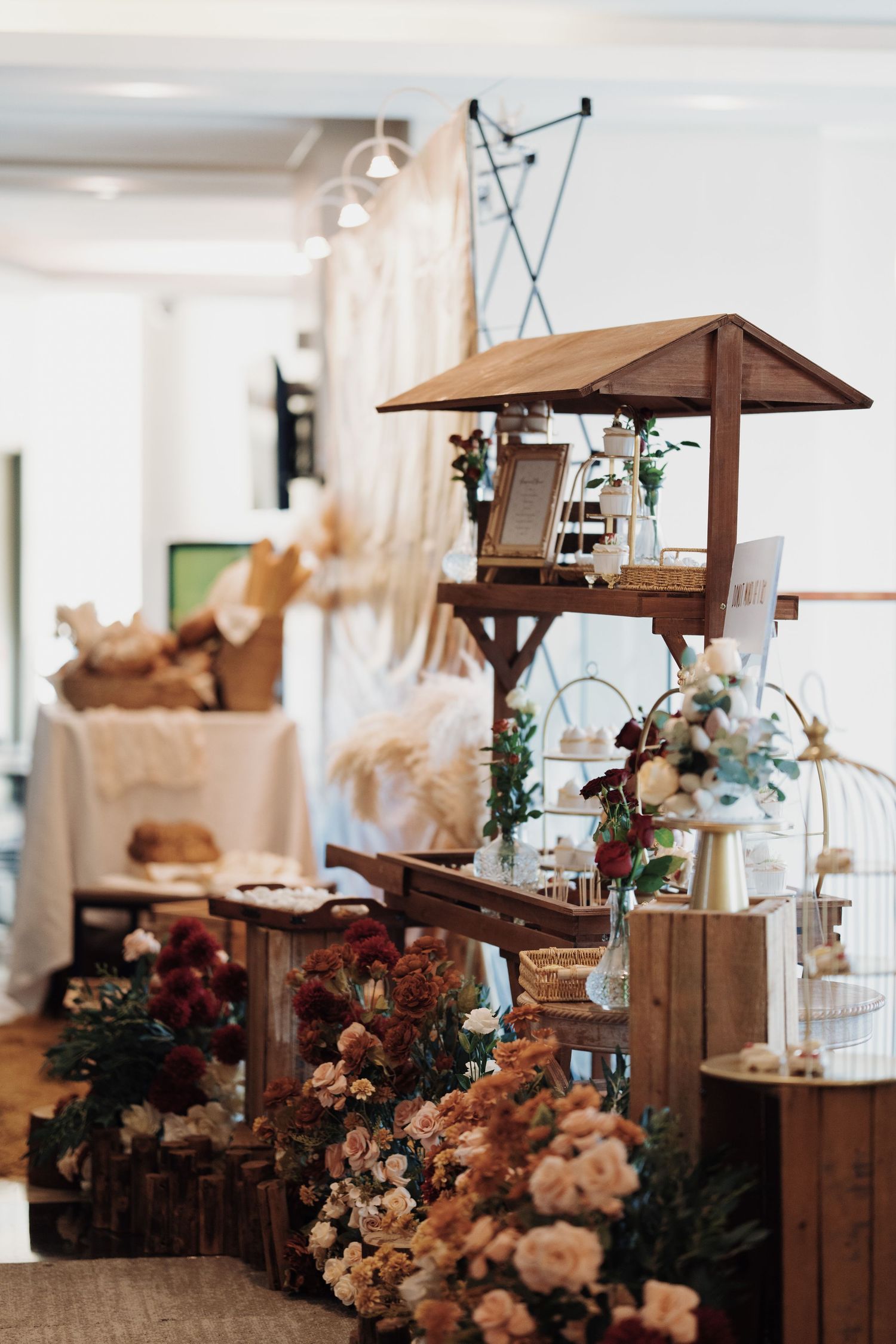 Rustic wedding dessert table featuring wooden crates, autumn-colored florals, and a sweet treat display