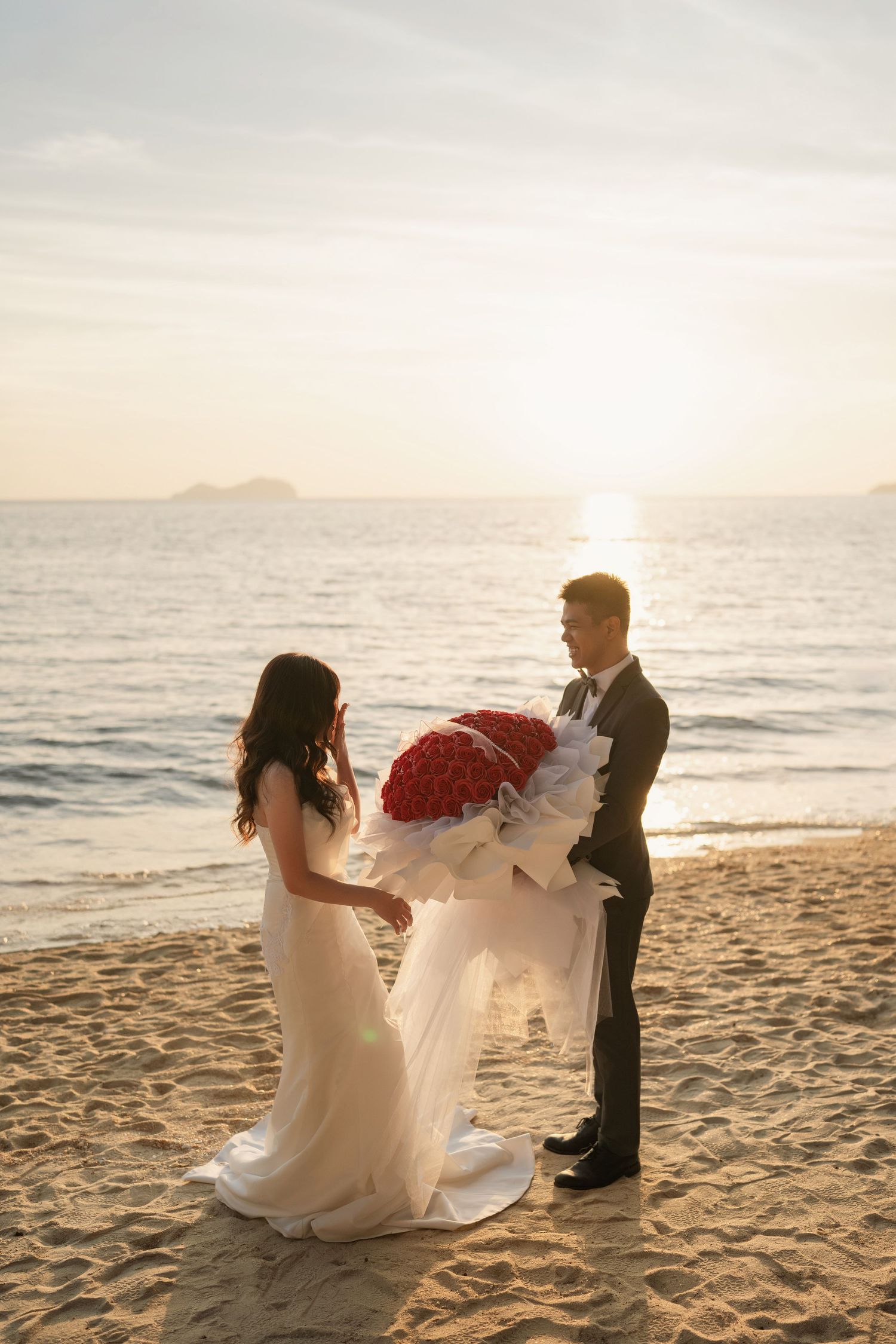 Wedding couple dances playfully on the beach during golden hour.