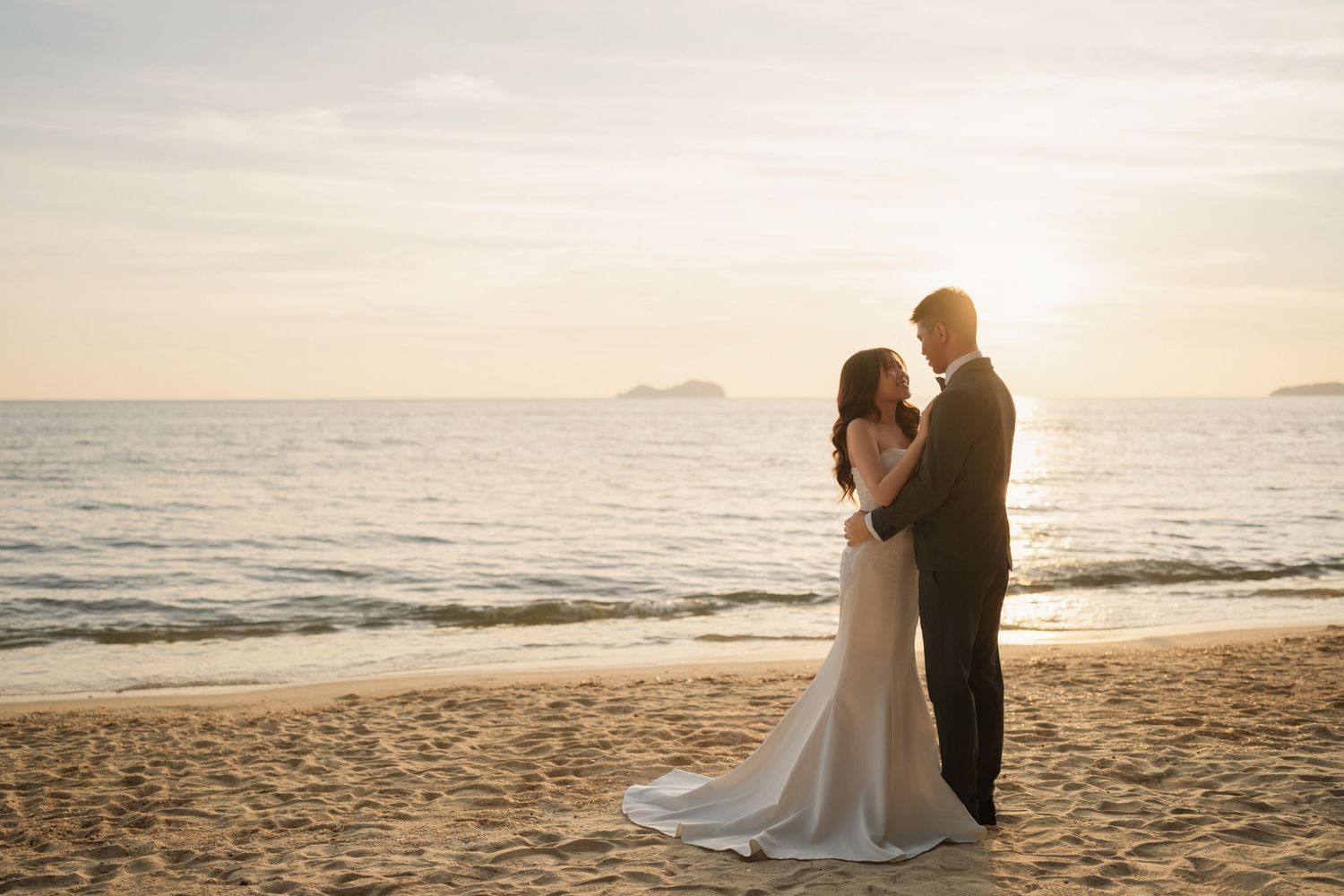 Romantic beach wedding photoshoot at sunset with ocean backdrop.