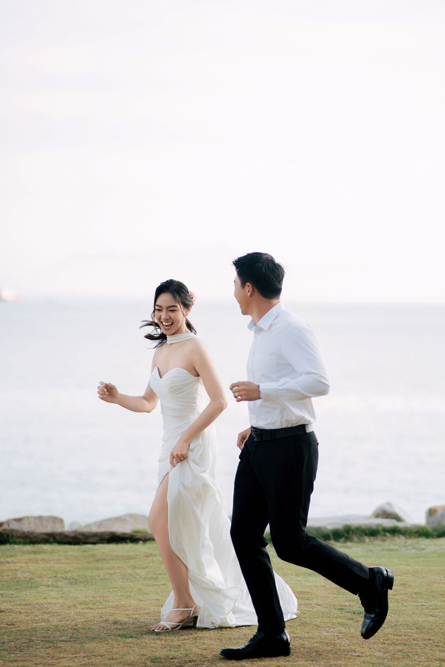 A playful couple runs and dances together during their wedding photoshoot.