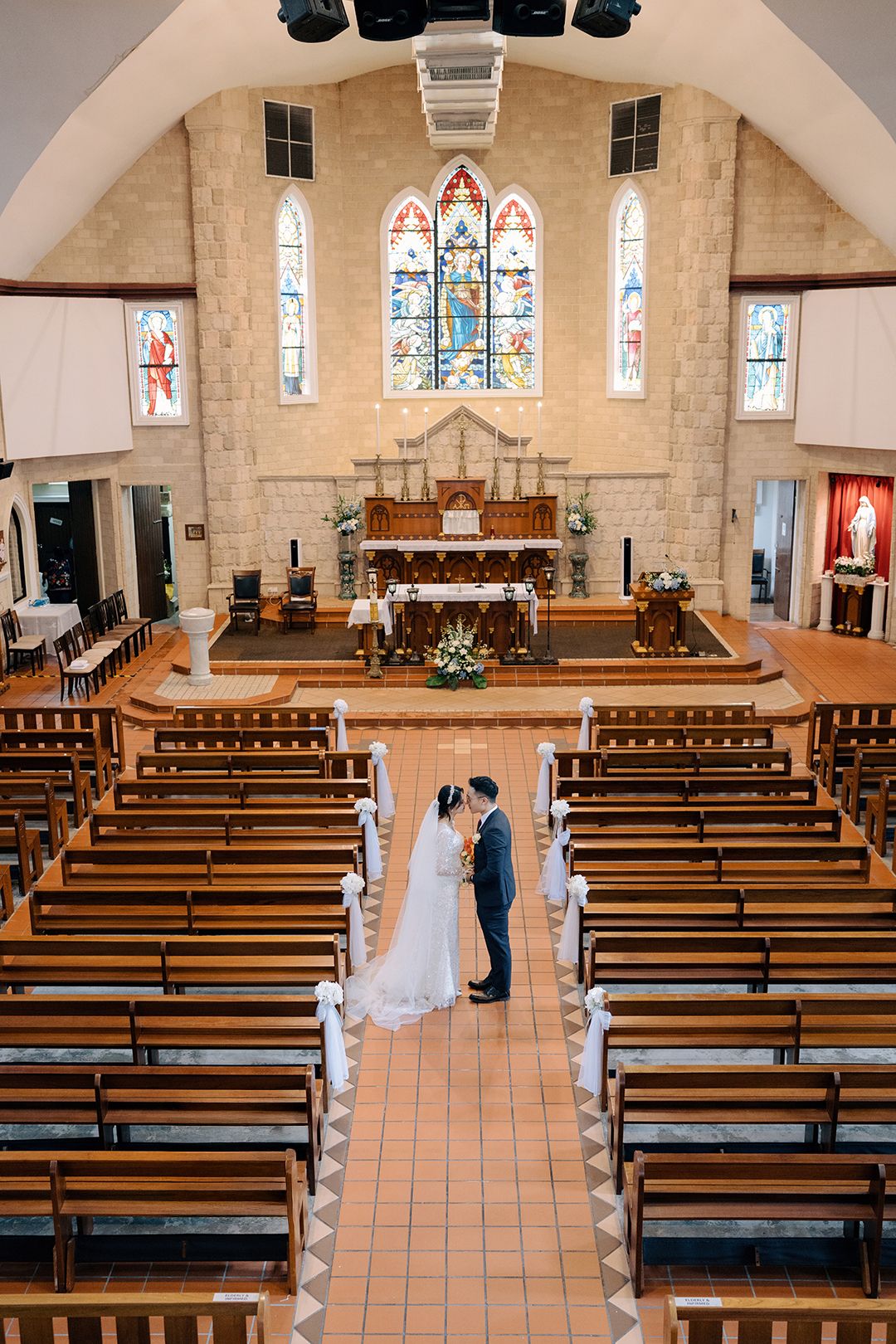 Architecture of a Catholic church featuring a wedding couple and colorful stained glass windows