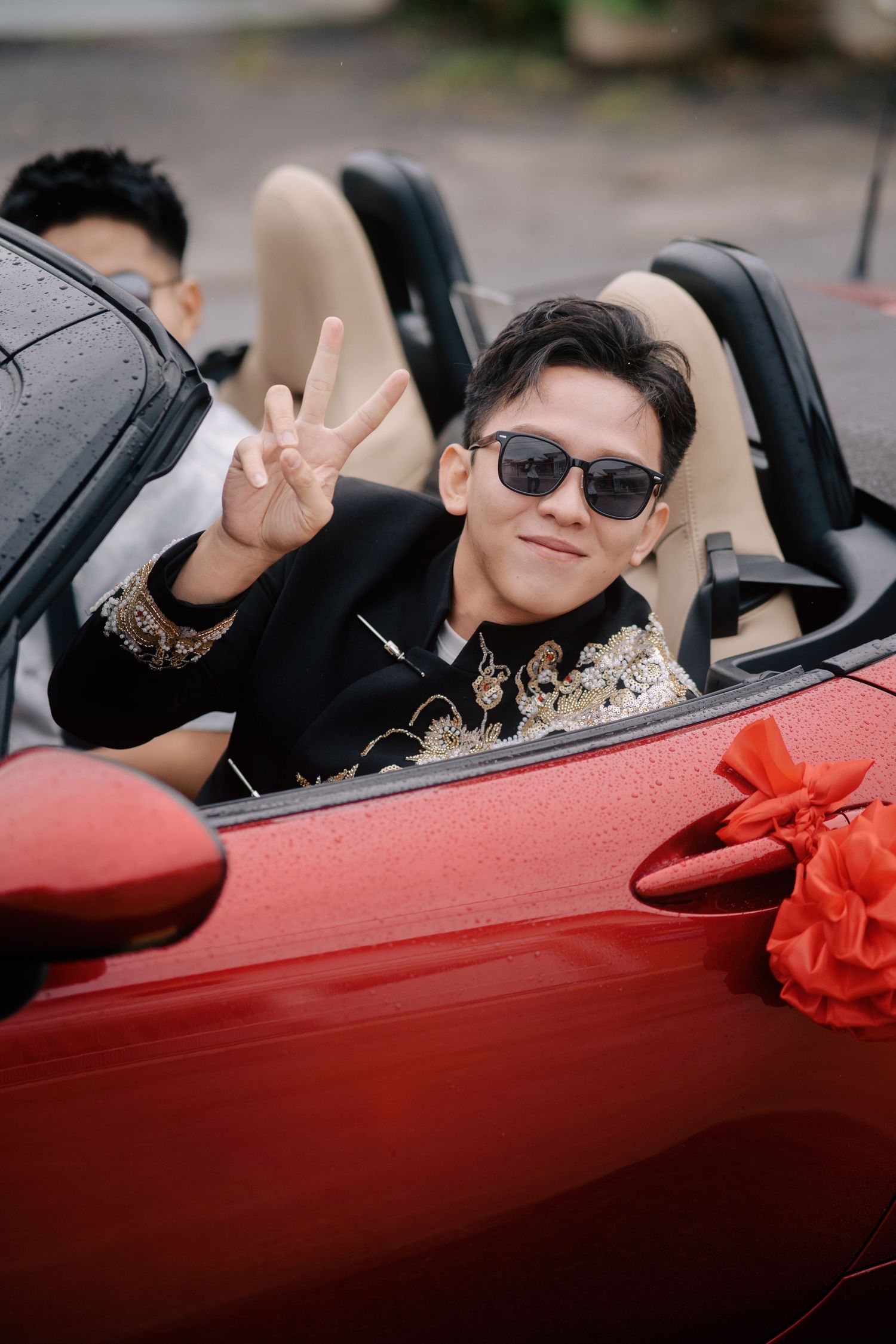 Groom in a modern Chinese wedding outfit arrives for the gatecrashing ceremony in a red convertible