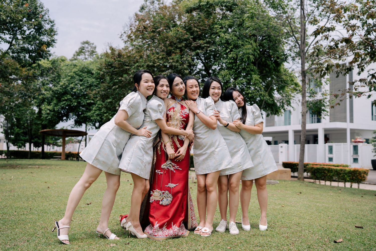 Bride and bridesmaids hugging during an outdoor photo session for a Penang Chinese wedding