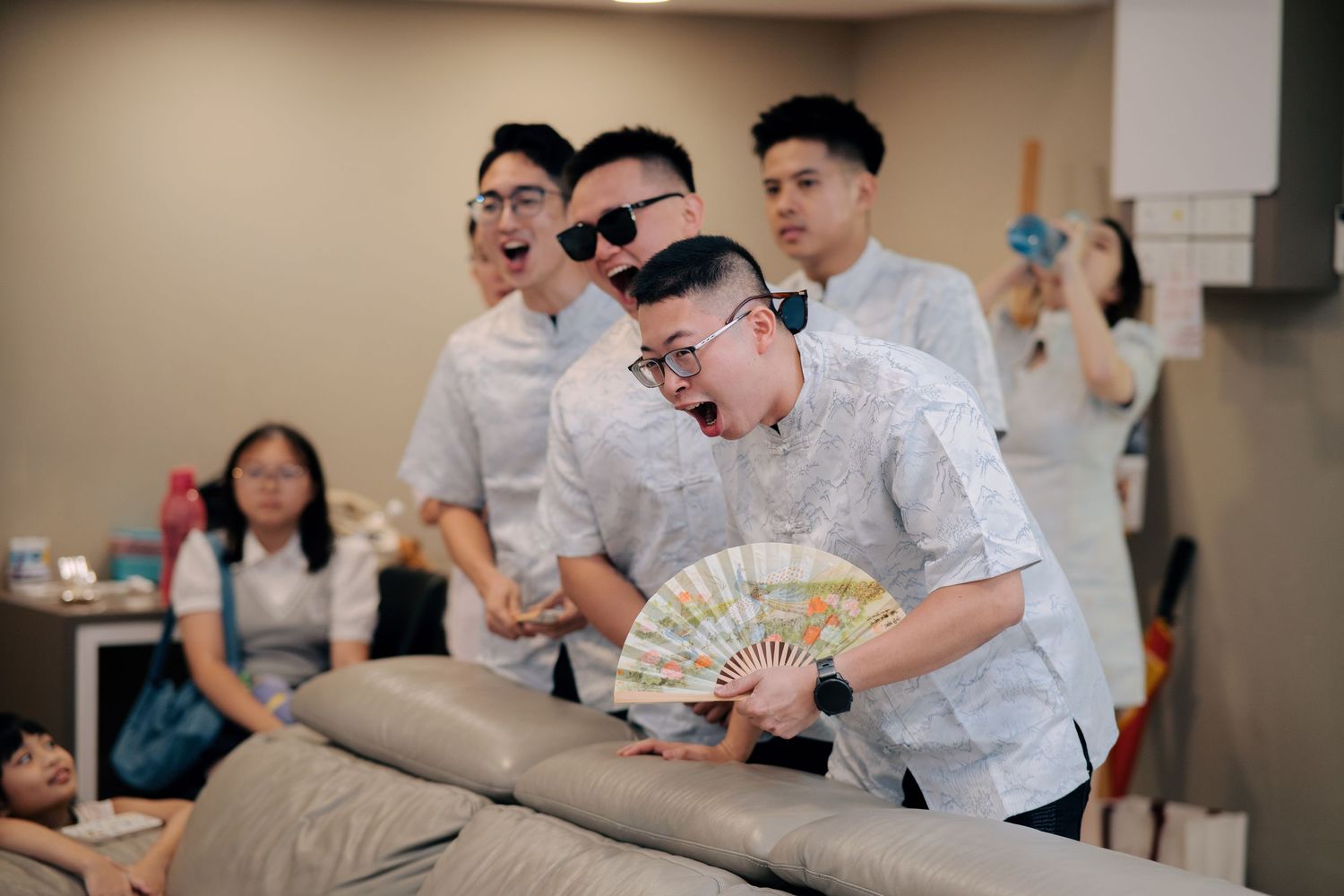 Excited groomsmen cheering during a traditional Chinese wedding gatecrashing challenge