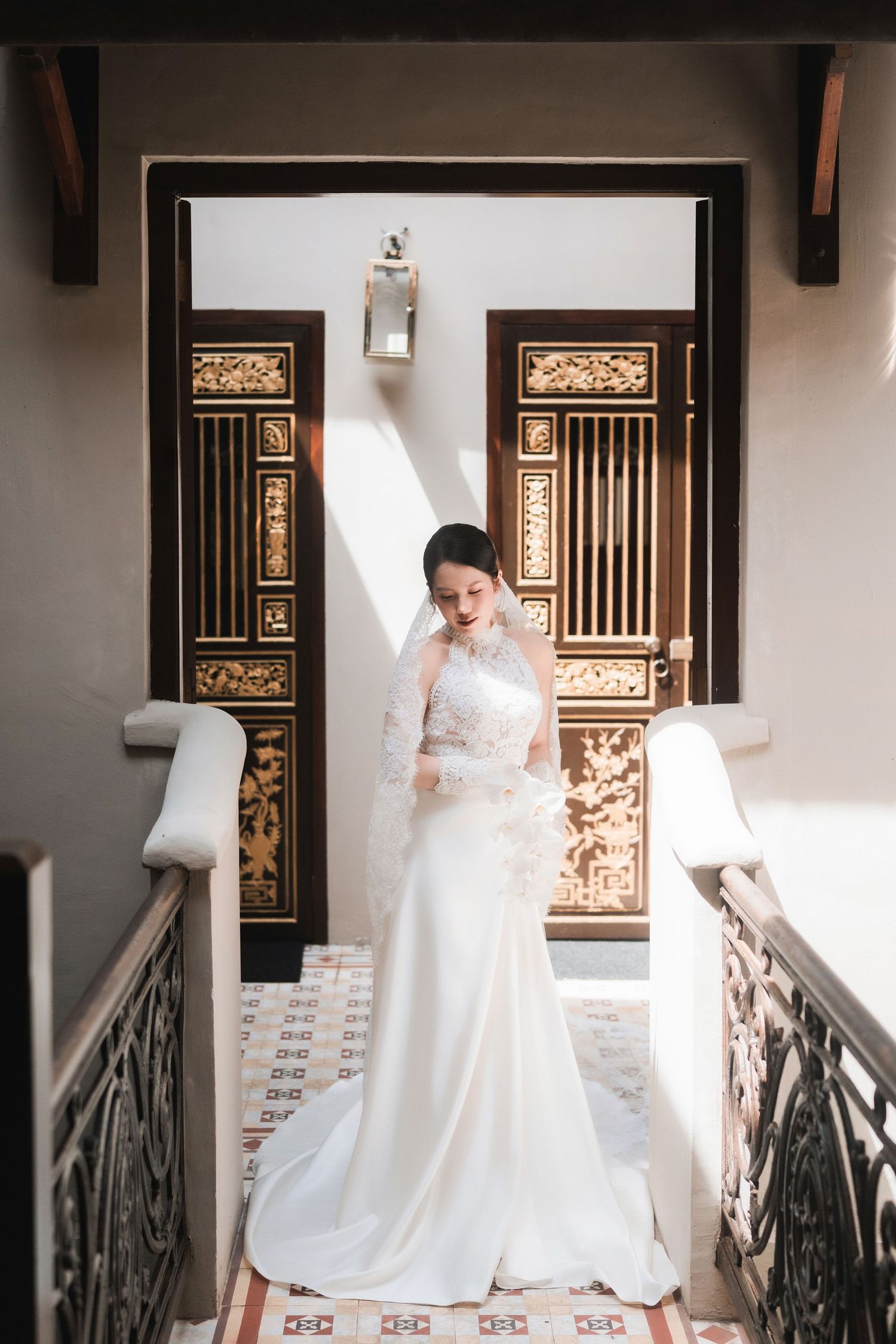 Wedding dress flowing gracefully against a backdrop of decorative wooden panels and railings.