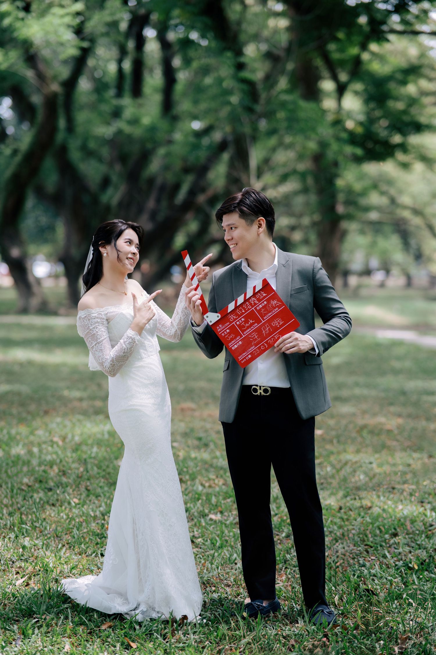 A playful wedding photoshoot in a park with the couple dancing and holding a red clapperboard.