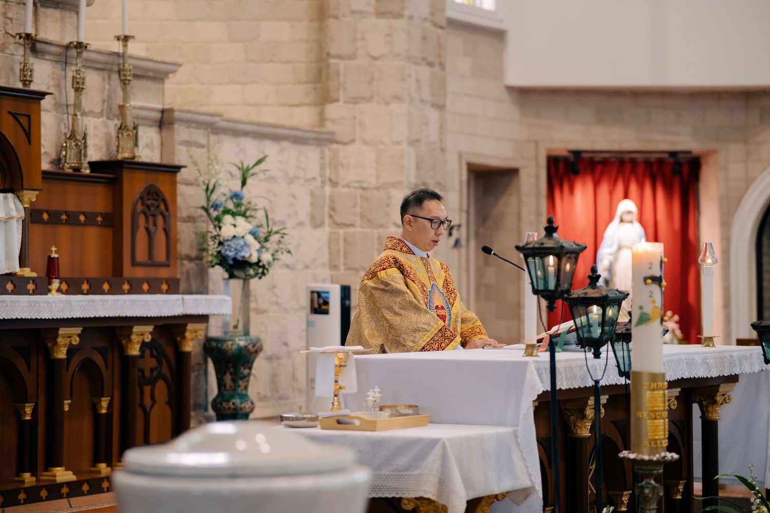 Priest officiating a Catholic church wedding ceremony at the altar with religious icons
