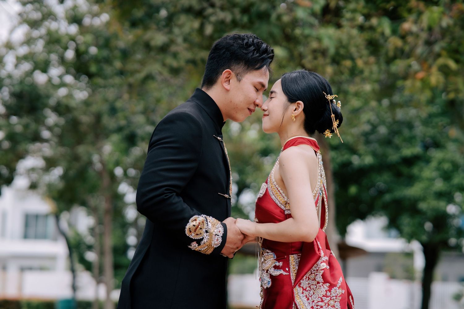 Intimate moment between a couple in traditional Chinese wedding attire featuring gold dragon and phoenix embroidery
