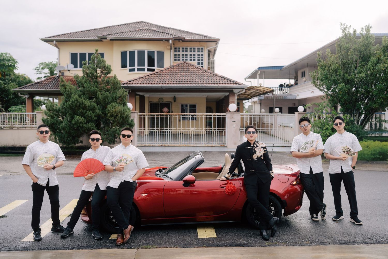 Groom and groomsmen with fans posing before traditional Chinese wedding gate-crashing games