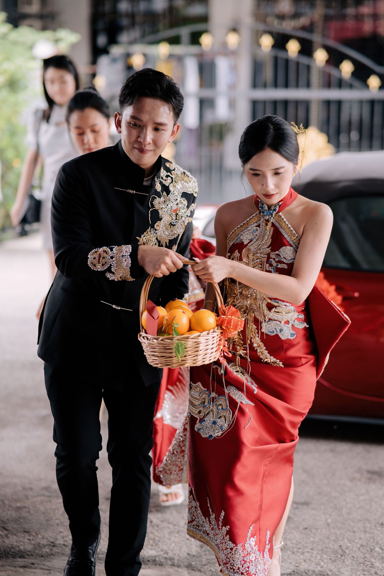 Bride and groom carrying a basket of oranges for a traditional Chinese wedding ritual