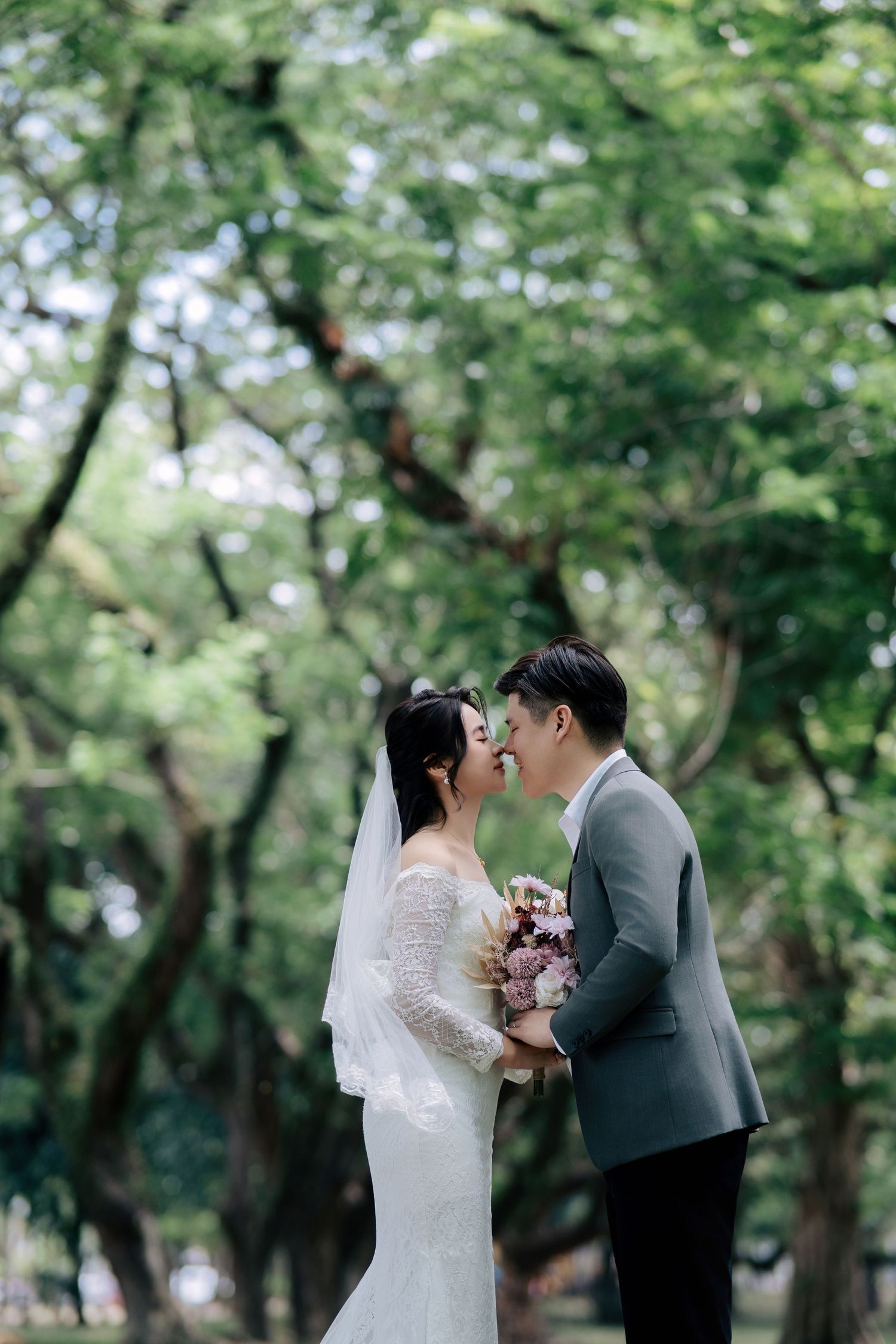 Intimate wedding moment captured in a leafy green park setting.