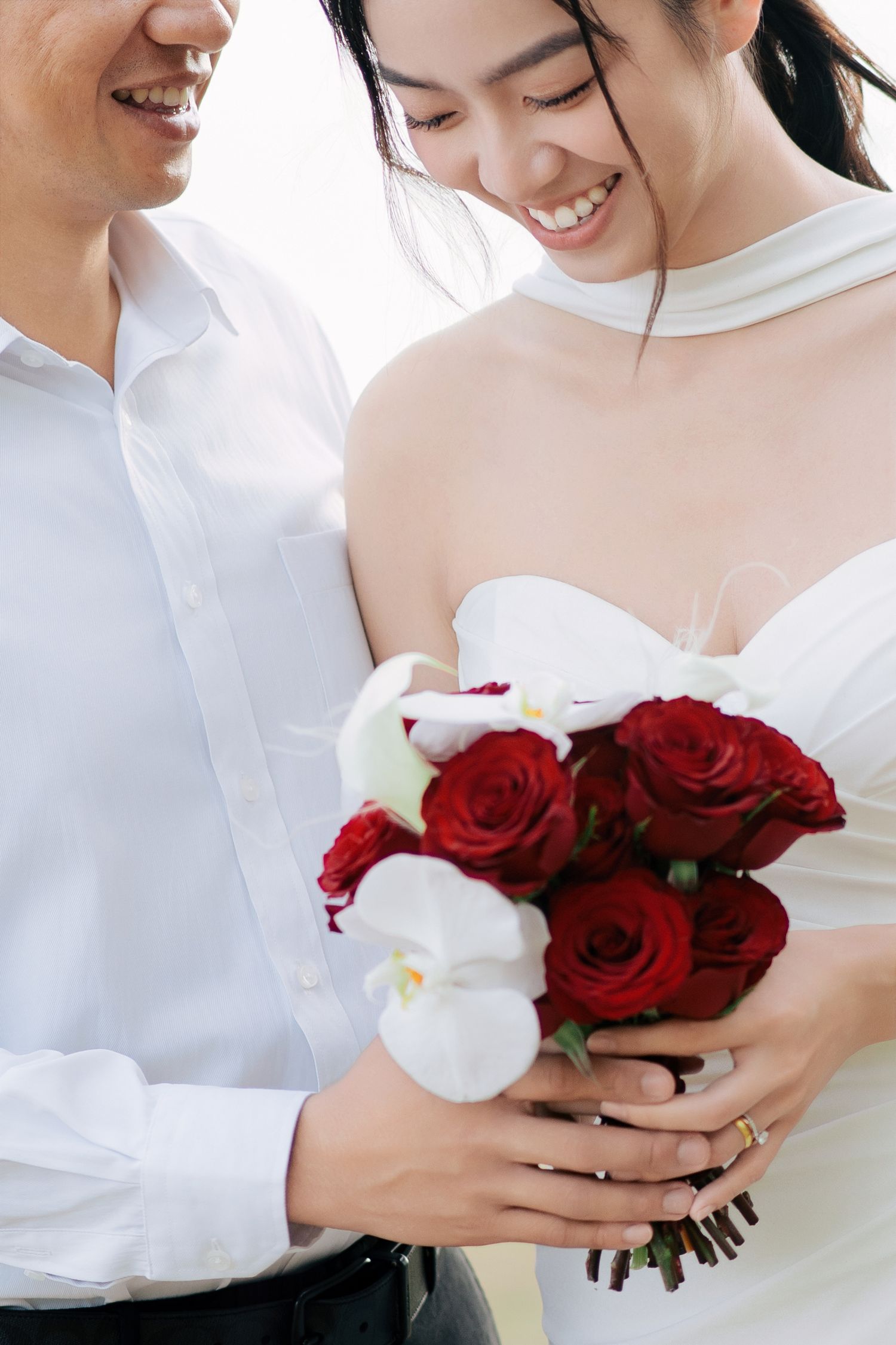 Close-up details of a bridal bouquet featuring red roses and white orchids.