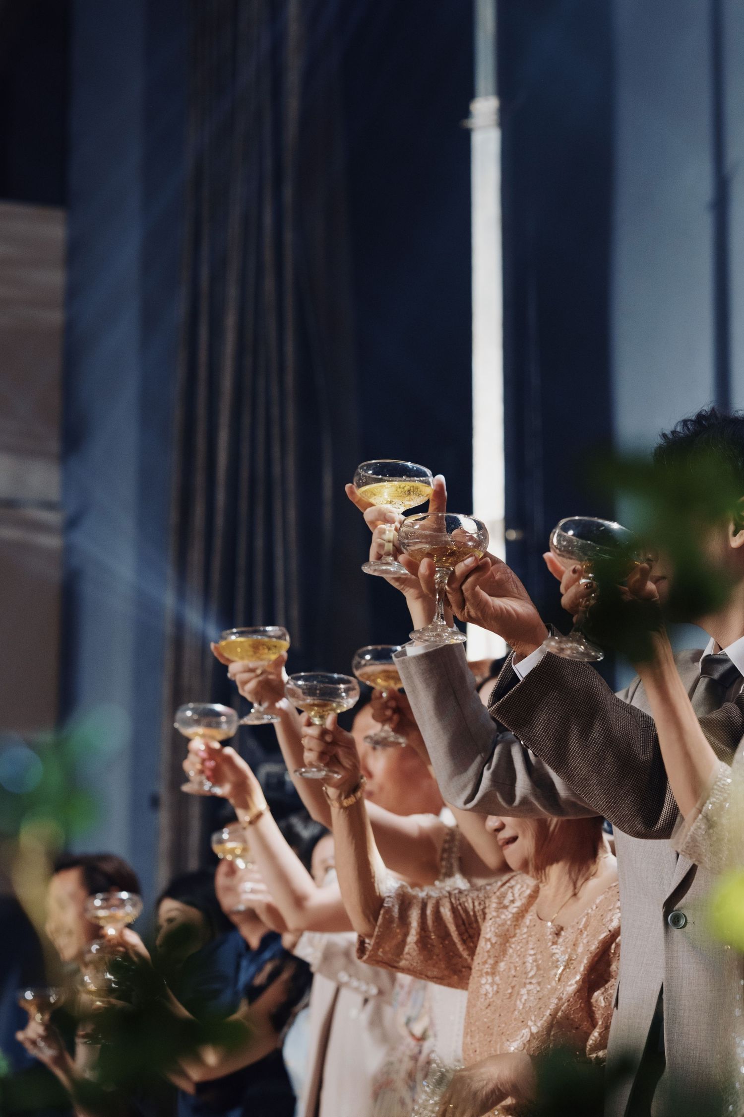 Wedding guests raising a toast with champagne coupes at a luxury reception dinner