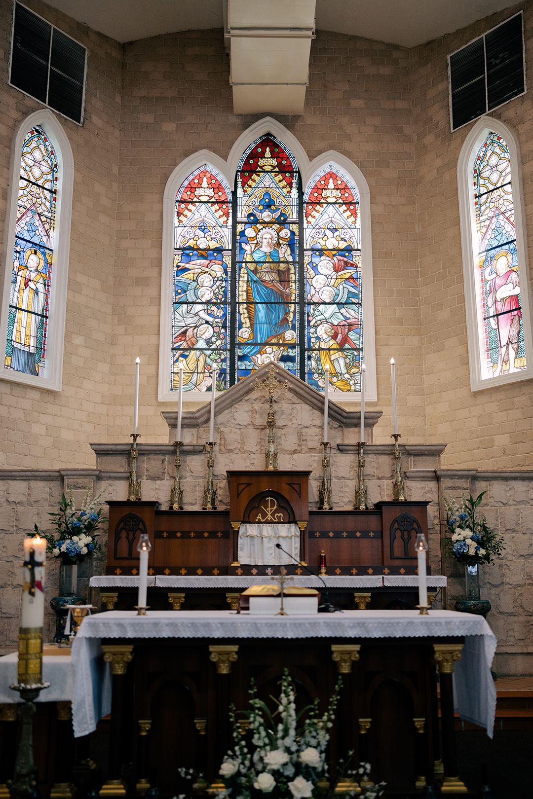 Detailed stone altar and stained glass windows, creating a sacred setting for a traditional church wedding ceremony