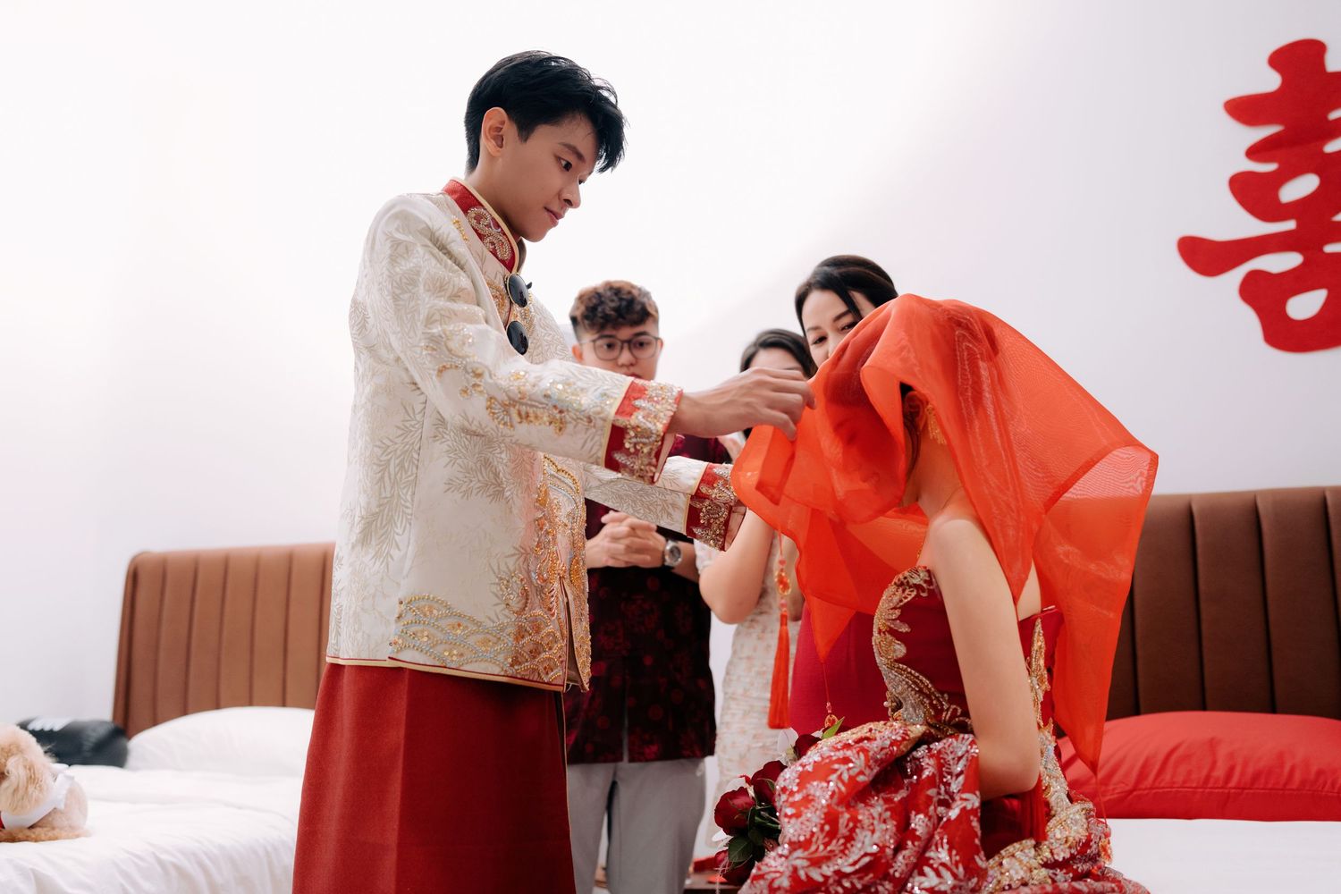 Wedding party members gather around a traditional Chinese bridal couch during celebrations.