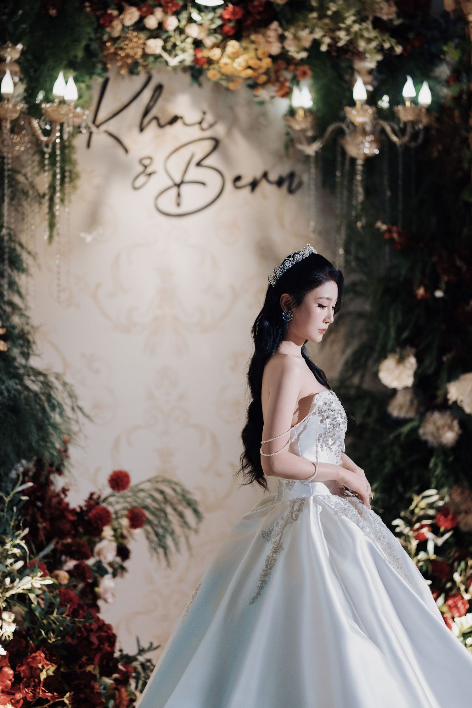 Close-up of a bride in a sparkling crown and ballgown, looking down thoughtfully at her wedding