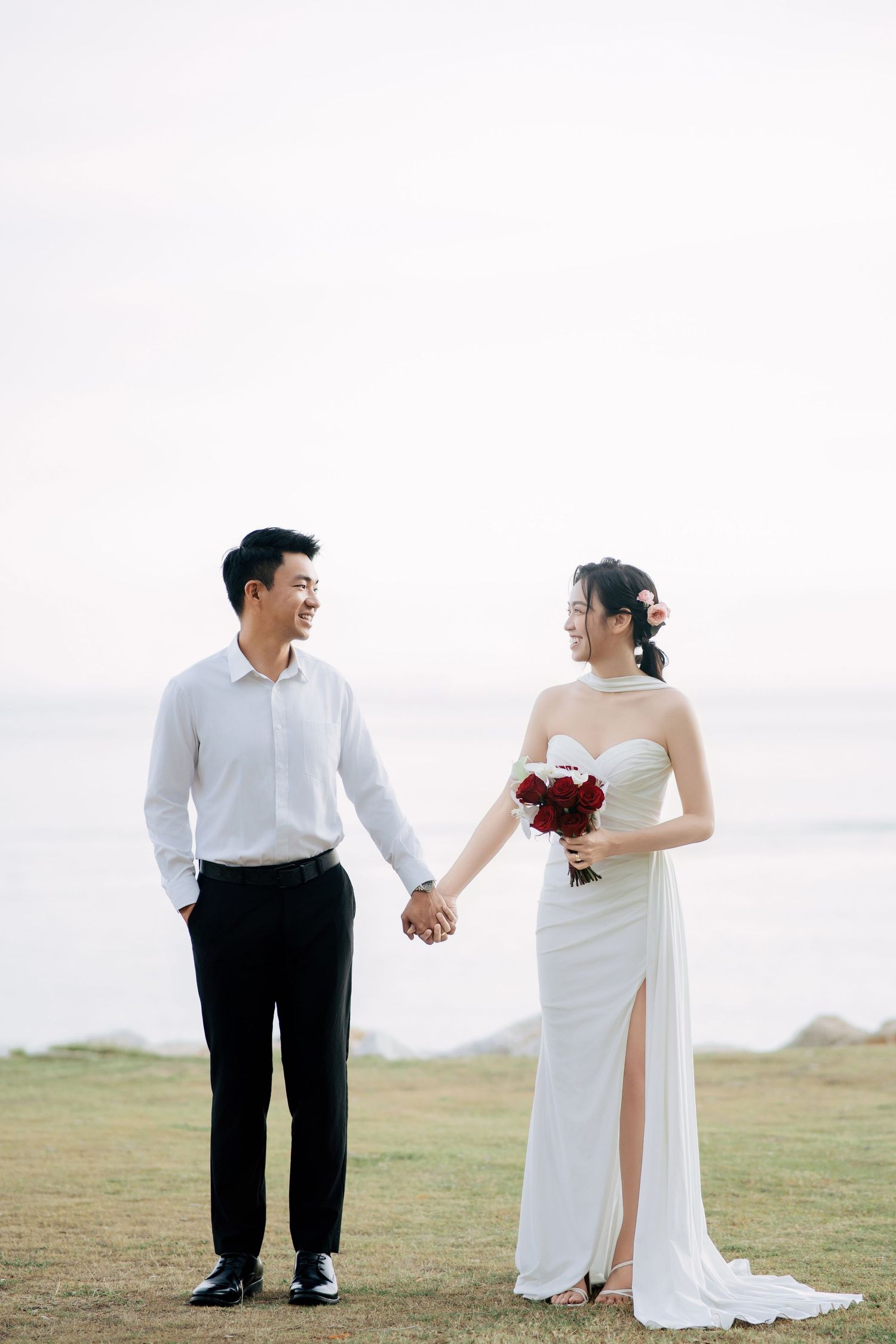 A couple shares joyful moments together on a scenic grassy hillside.