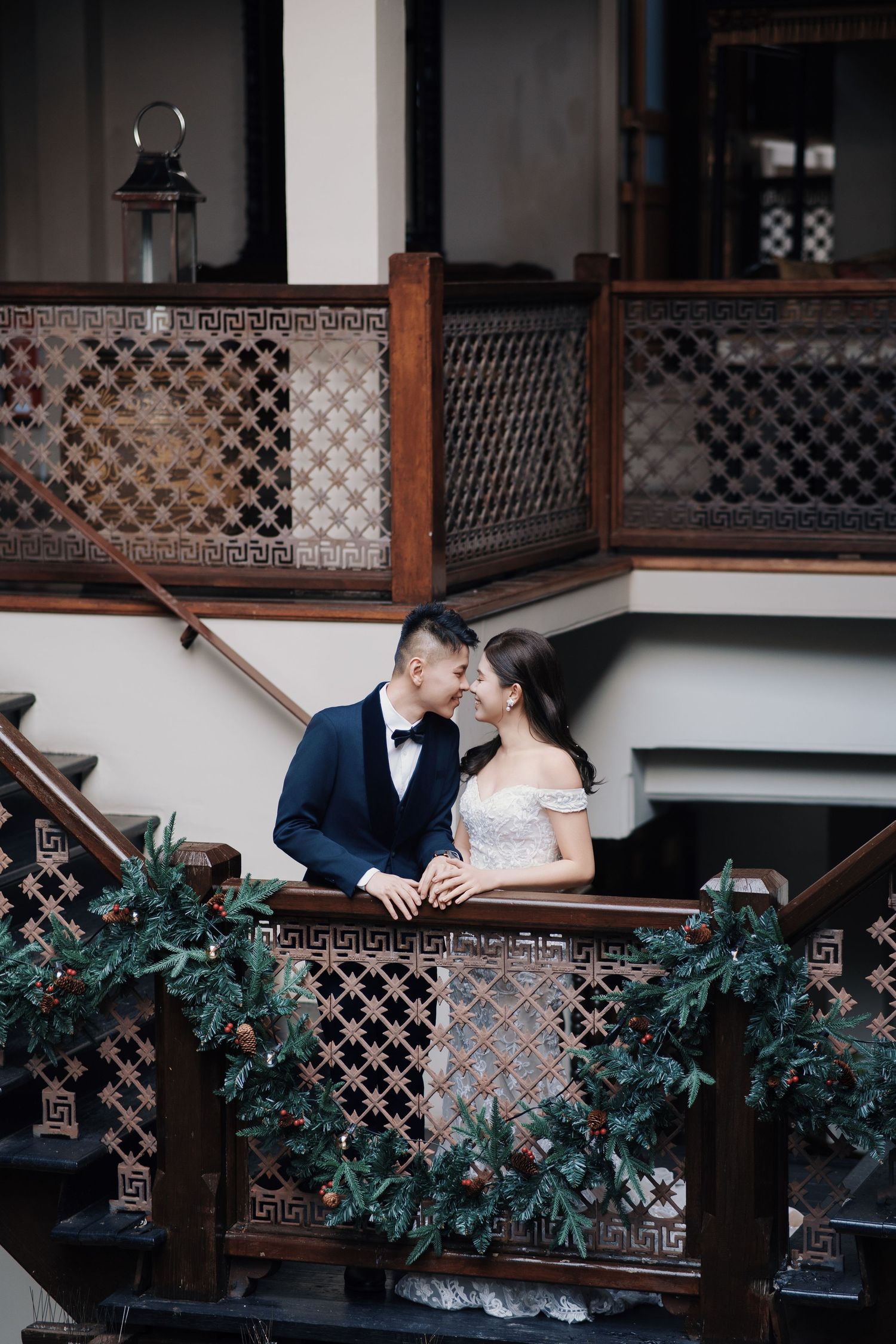 A bride and groom lean in close on a festive heritage staircase at Seven Terraces, a premier George Town wedding venue
