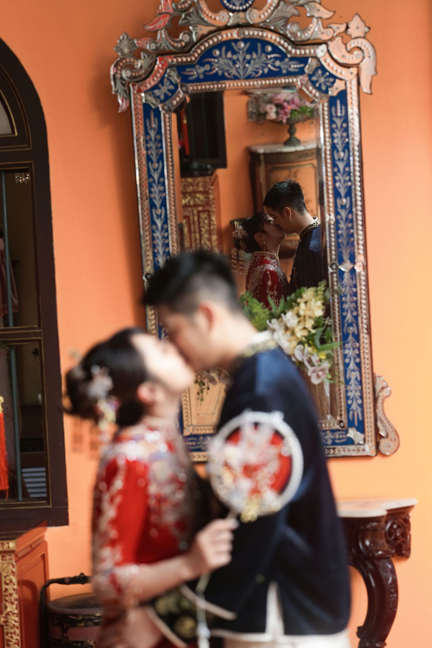 Creative Peranakan wedding photography showing a couple’s kiss reflected in a Venetian-style mirror