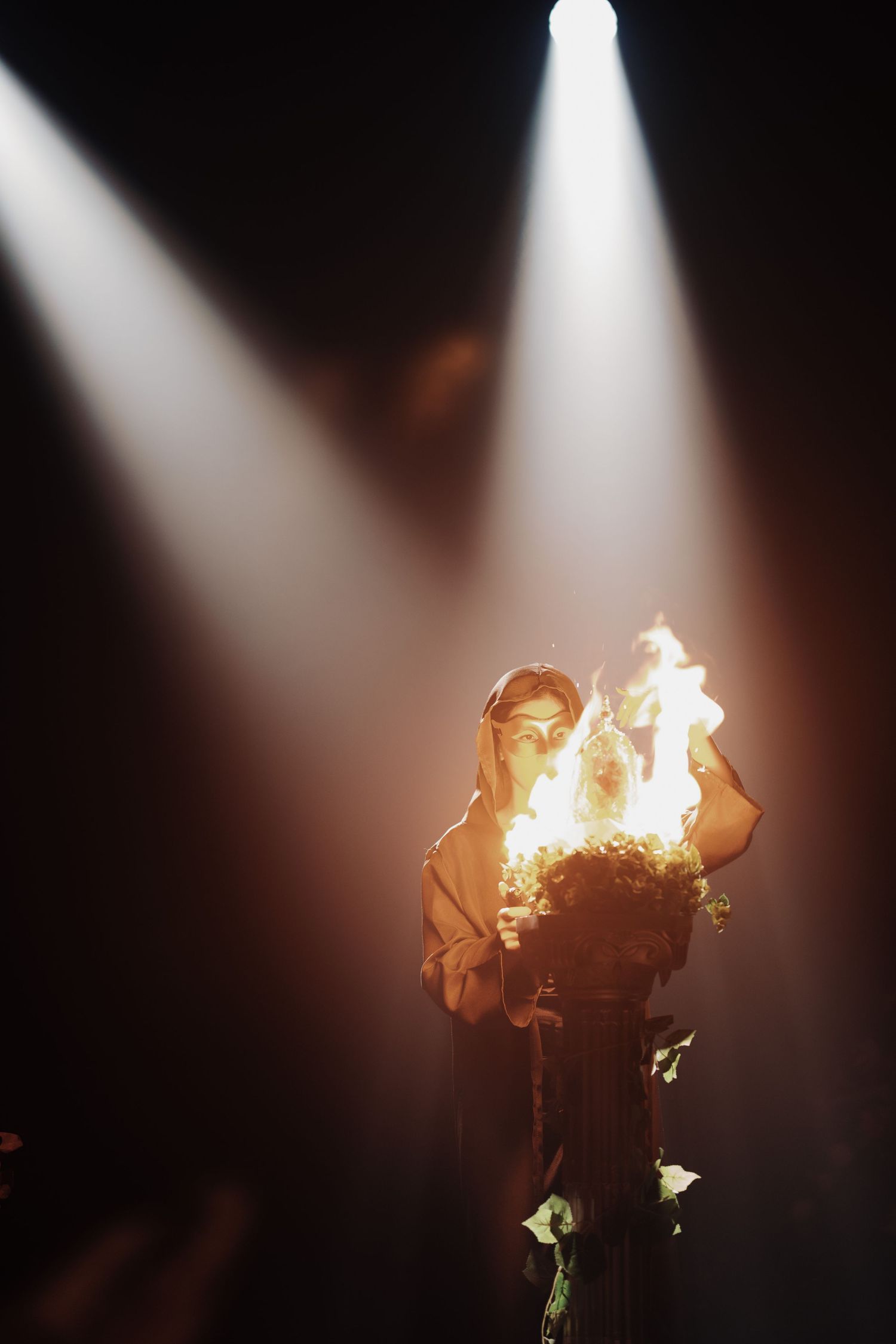 Hooded figure performing a dramatic fire ritual under a spotlight at an enchanted Beauty and the Beast theme wedding