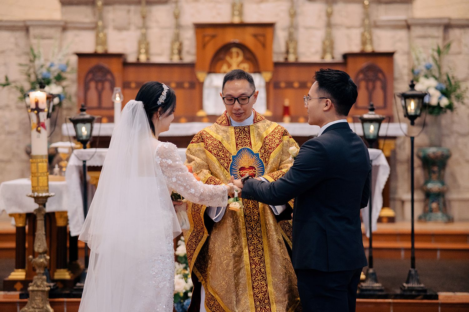Priest joining the hands of a bride and groom during a traditional Catholic wedding ceremony
