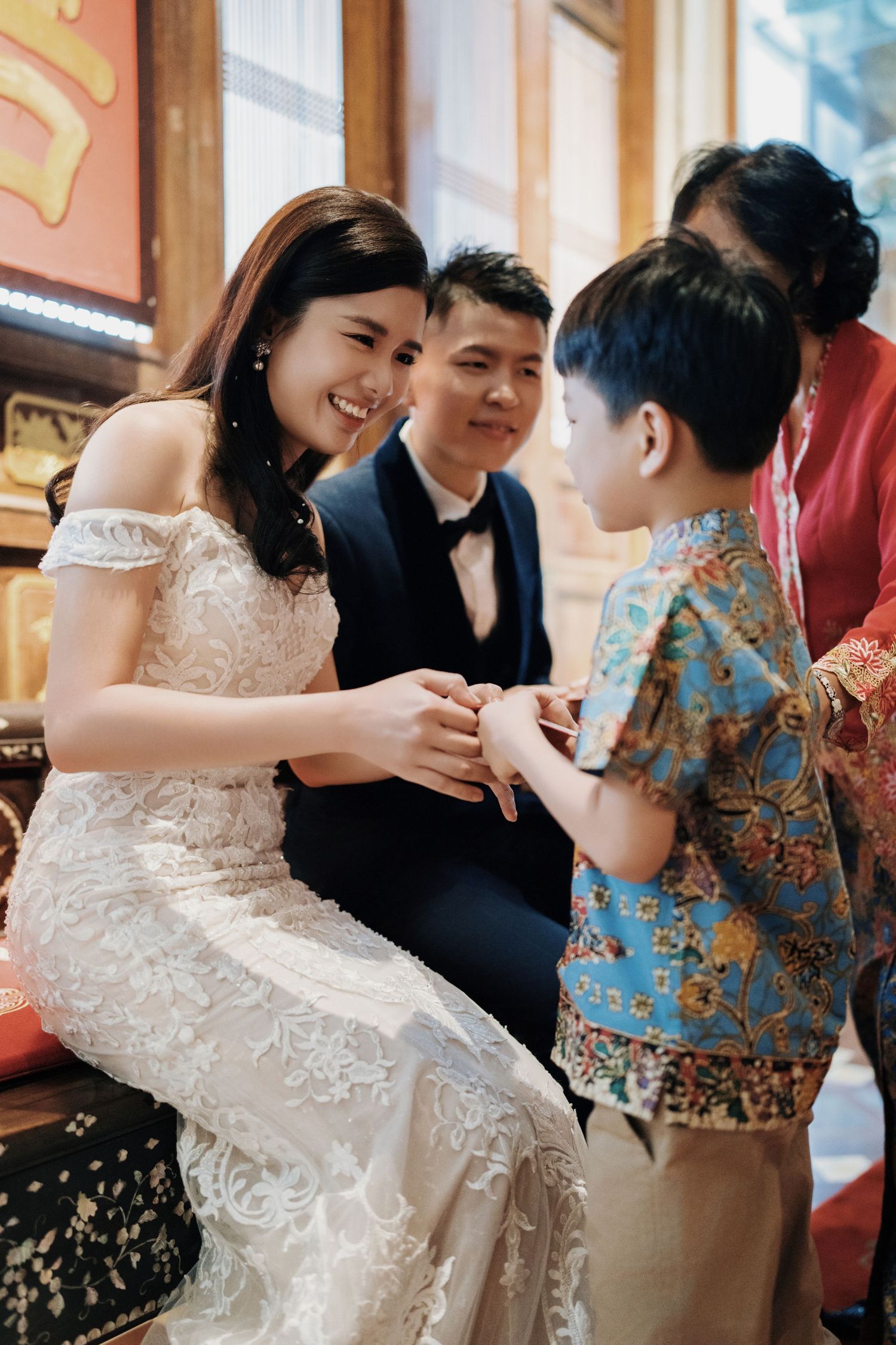 Smiling bride giving a traditional red packet to a young guest at her Seven Terraces wedding