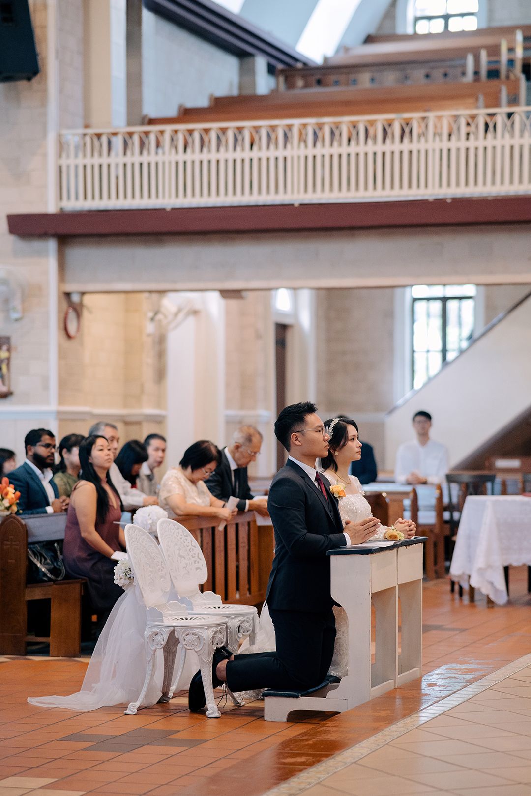 Bride and groom kneeling for prayer during a traditional Catholic wedding ceremony