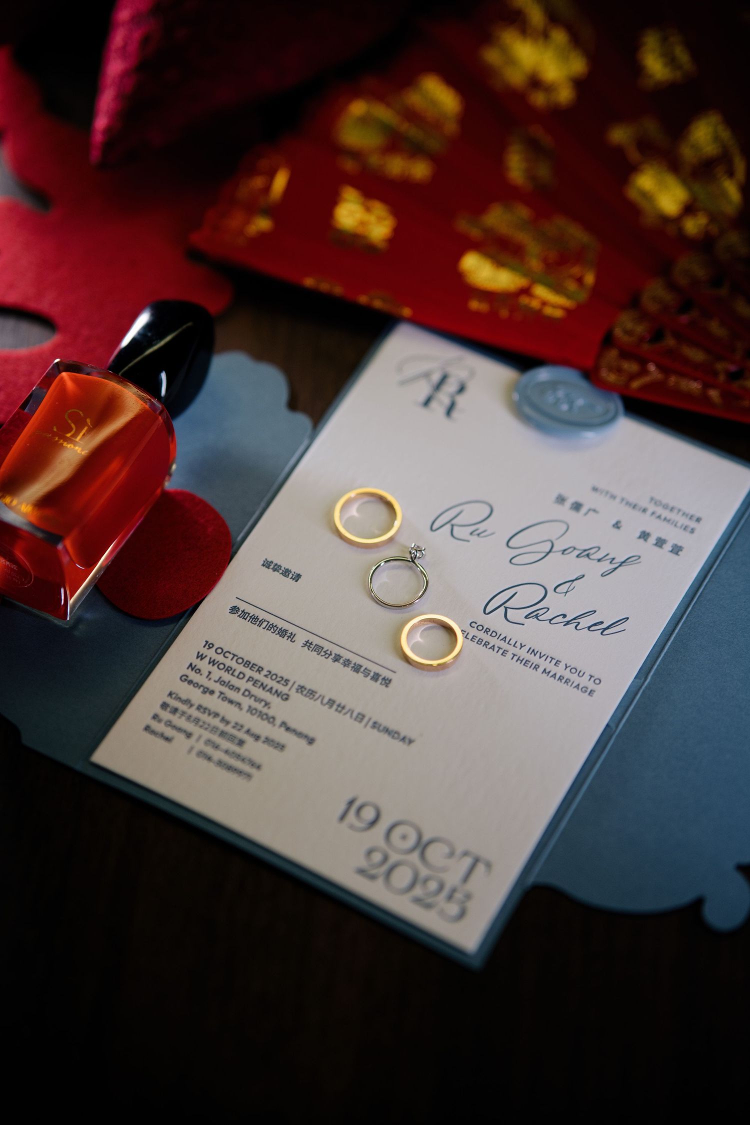 Wedding rings and invitation cards displayed on a dark surface with dramatic lighting.